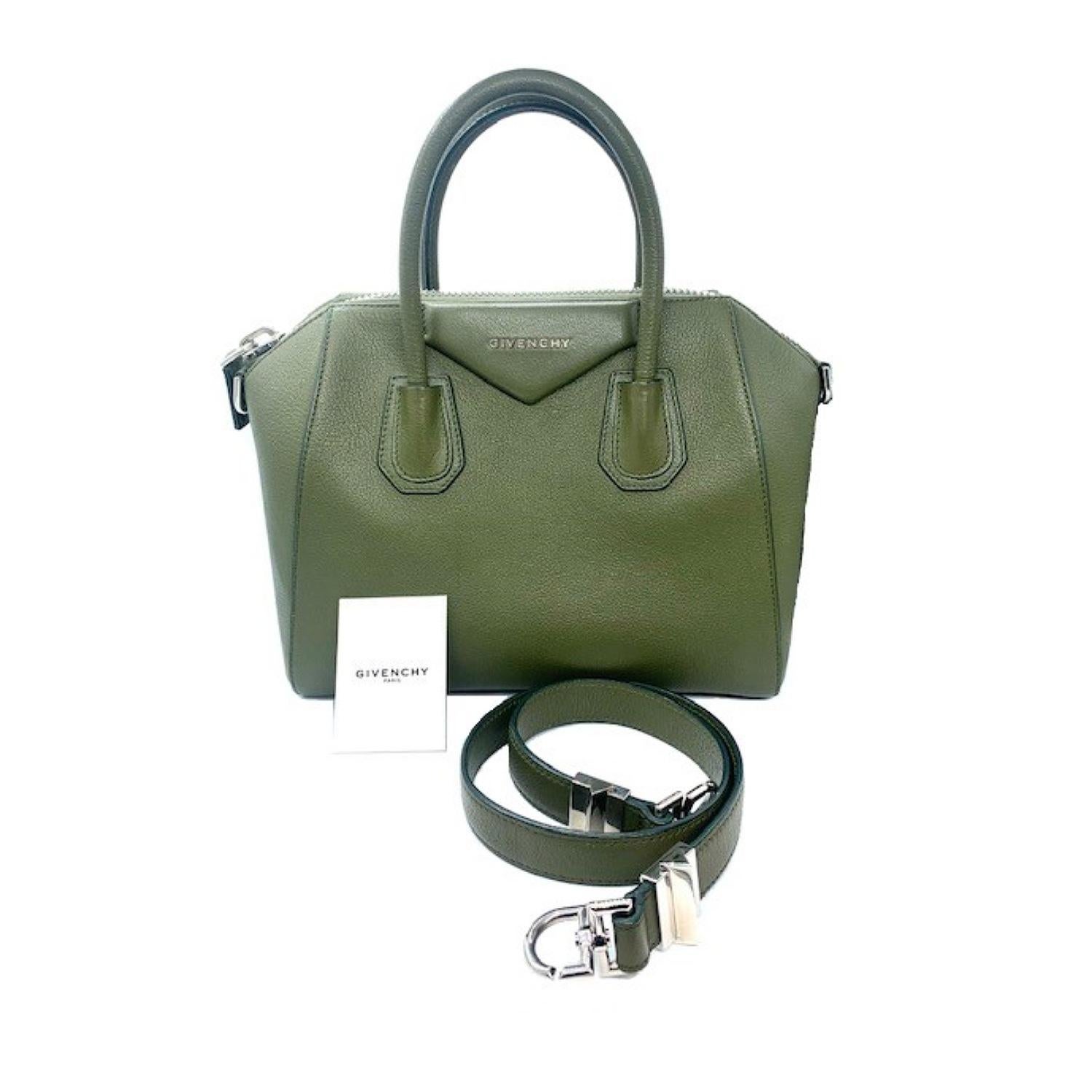 This stylish satchel is crafted of richly textured goatskin leather in olive green. The bag features sturdy rolled leather top handles, a shoulder strap with silver clasps and extended sides. The top opens with a zipper to a black fabric interior