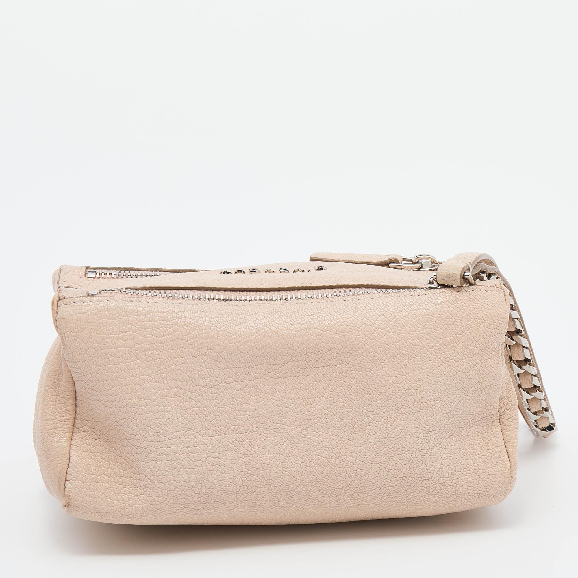 This lovely wristlet clutch is by Givenchy. It has been made in Italy from leather and shaped to perfectly carry your necessities. The sleek beige piece has a simple design and is equipped with two zippers that are held by a chain-leather strap. The