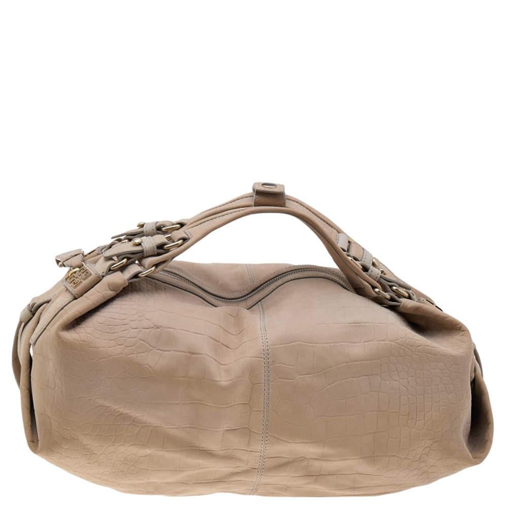 Add a luxurious touch to your collection of accessories with this Givenchy hobo. It is made from embossed leather. It comes in an understated beige hue. It is styled with short handles, fabric interior, and enough space for essentials. It is