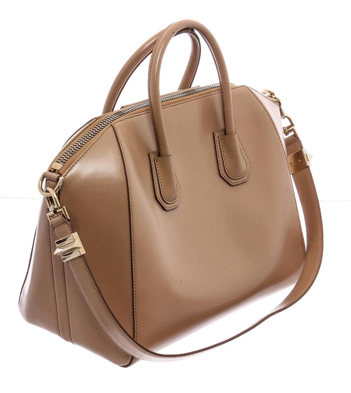 Beige smooth calfskin Givenchy Large Antigona satchel with silver-tone hardware, dual rolled top handles, single detachable flat shoulder strap, logo hardware embellishment at front, protective feet at base, tonal canvas lining, three interior