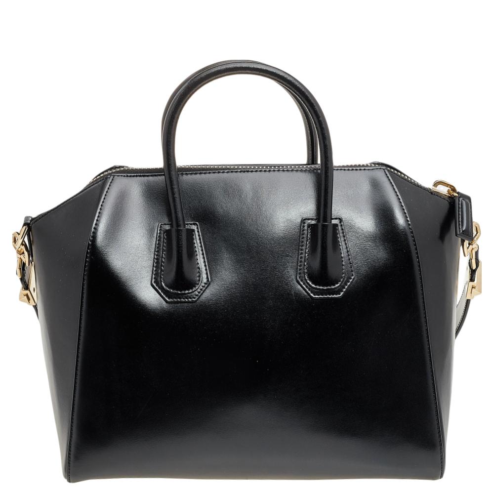 Chic and charming, this Antigona satchel from Givenchy will amp up your trend factor almost immediately! It is masterfully crafted from black leather and features a gold-toned logo lettering on the front. It is completed with dual handles, a