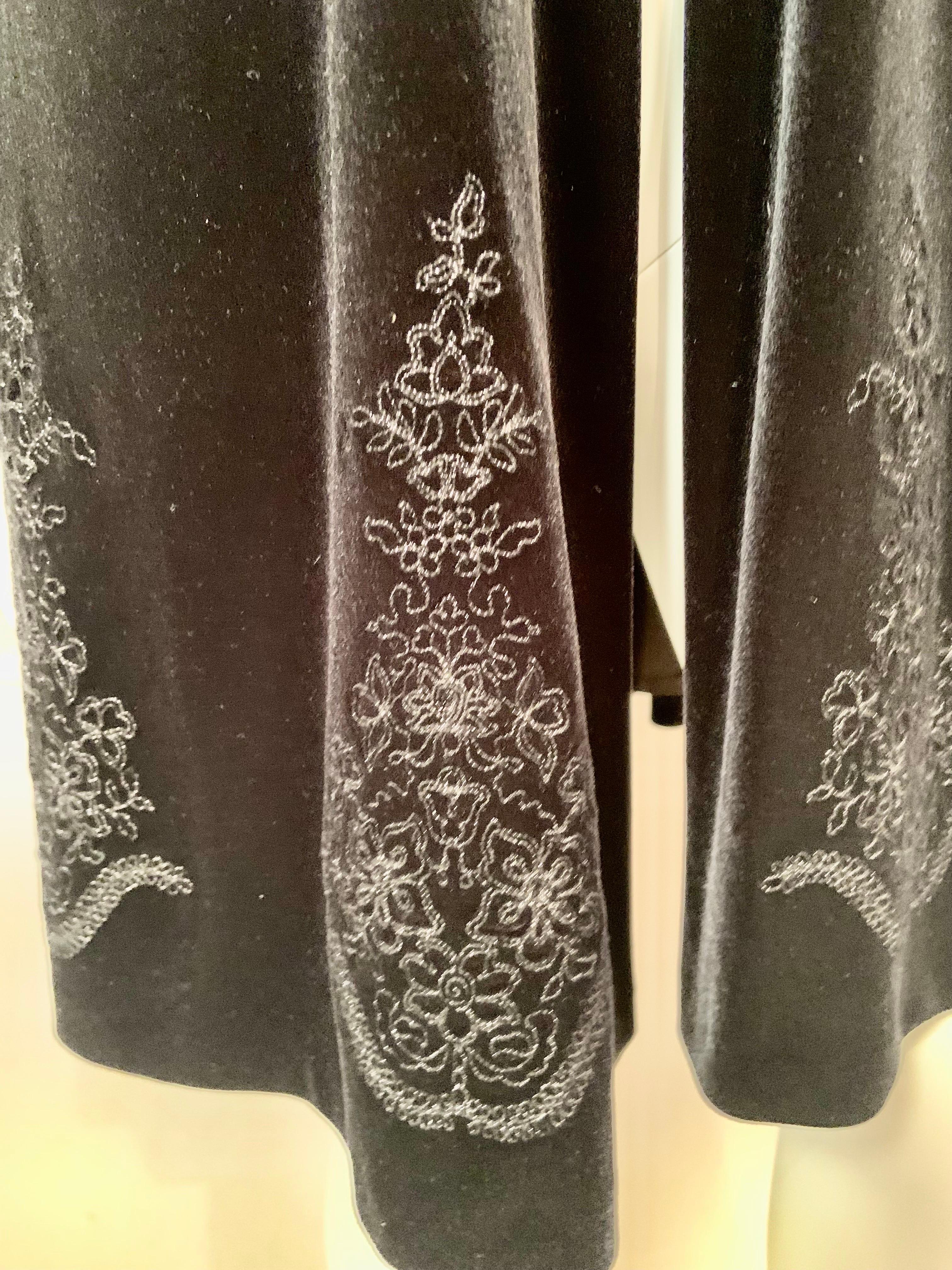An elegant jacket from Givenchy is made from black velvet with a black frog closure at the neckline.  The hemline of the jacket has eight Fortuny inspired silver motifs, bringing a touch of old world glamour to the piece.  The jacket is lined in