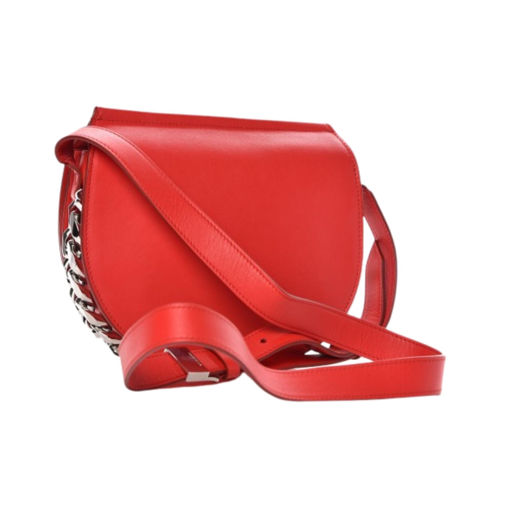 This unique saddle bag from Givenchy is crafted in red calfskin leather with polished silver chains along the sides and bottom. The bag also features a shoulder strap and a flap that has a magnetic snap closure which opens to a beige interior with a