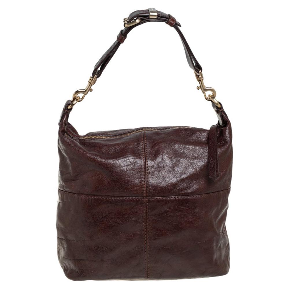 Crafted from leather, this dark brown hobo from Givenchy is designed with minimal style details but with high attention to craftsmanship so that it may assist you with durability. The spacious interior of the bag is lined with fabric and secured by