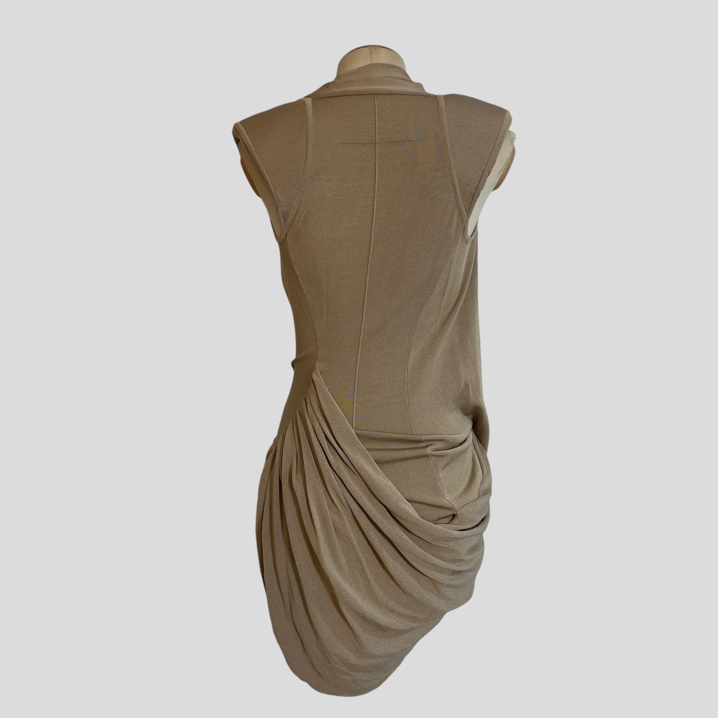 Piece Description: This beige draped dress from Givenchy's 2010 collection features an elegant, Grecian-inspired silhouette. Crafted with soft, flowing fabric, it includes structured shoulder pads that add a bold, architectural touch to its delicate