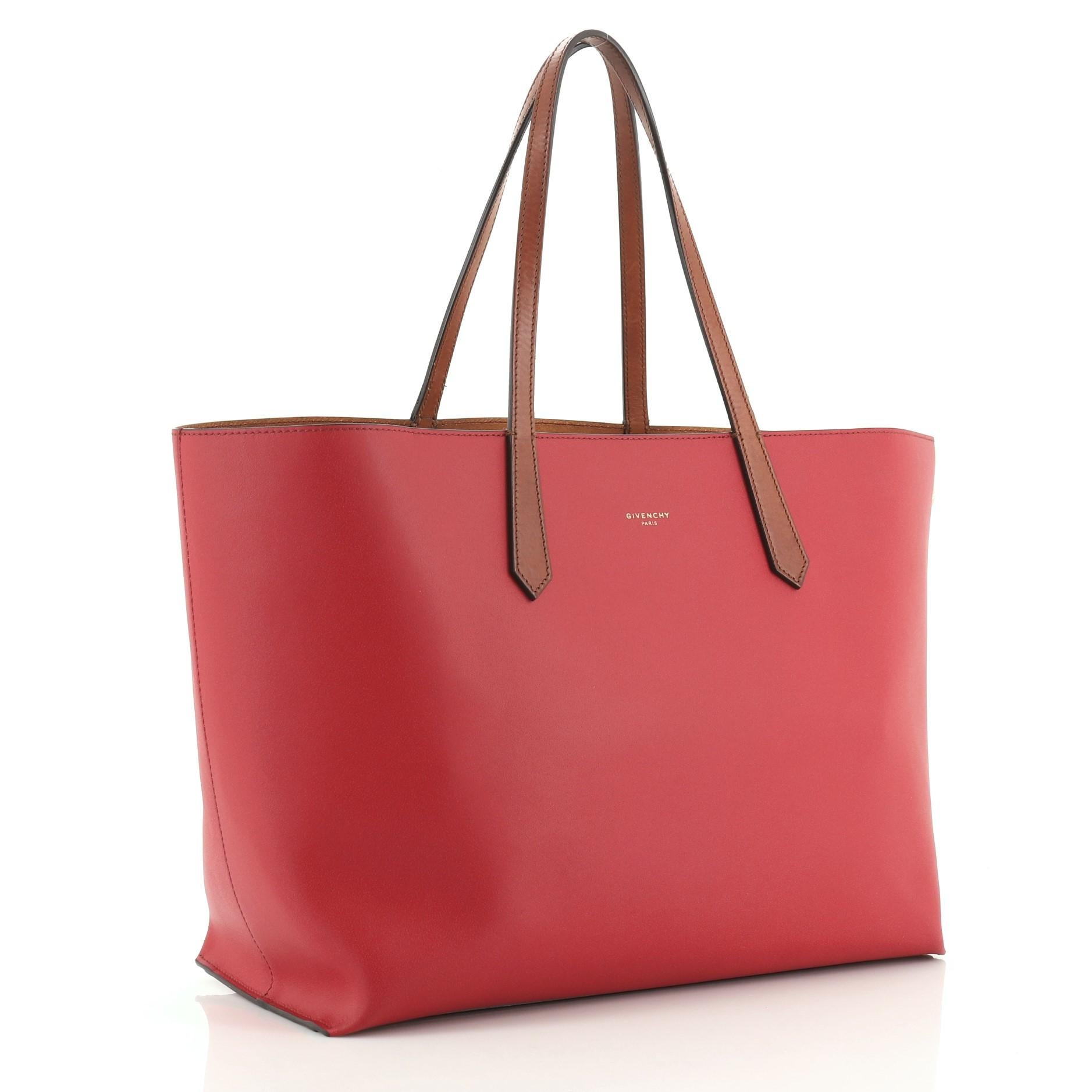 This Givenchy GV Tote Leather Medium, crafted in red leather, features dual slim leather handles and gold-tone hardware. Its wide open top showcases a gold leather interior with slip pocket.

Condition: Great. Minor wear on exterior, darkening, wear