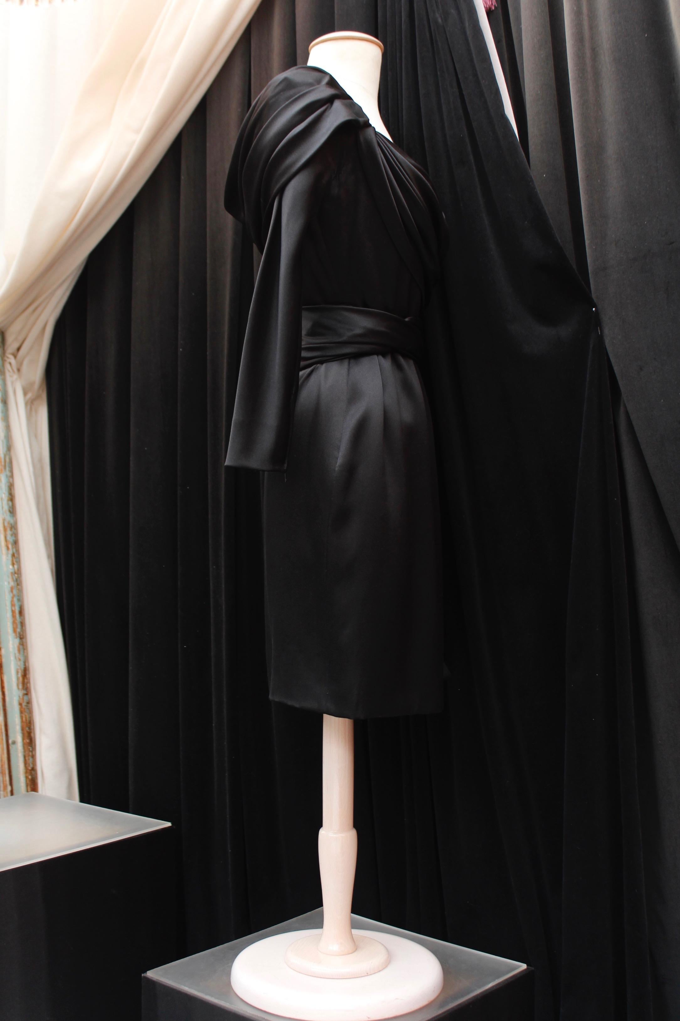 GIVENCHY HAUTE COUTURE (Made in France) Gorgeous short evening sheath dress composed of black silk satin. It features long sleeves and wide  off-the-shoulder neckline, a wrap cut decorated with pleats and drape effect, and a cinched waist