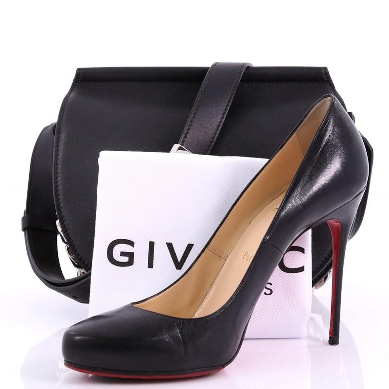 Ce mini-sac en cuir Infinity de Givenchy:: confectionné en cuir noir:: est doté d'une bandoulière réglable:: de chaînes sur les côtés et le fond:: et d'un matériel de couleur argentée. Son rabat à fermeture magnétique s'ouvre sur un intérieur en