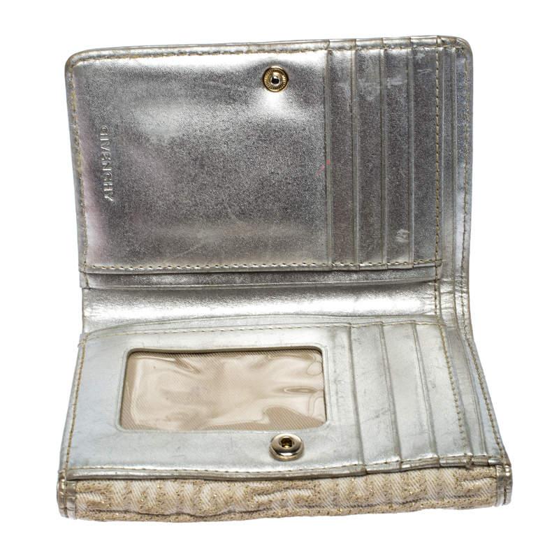 This stylish compact wallet by Givenchy has been crafted from ivory fabric with gold detailing. It features the brand logo in the front and opens to reveal an interior lined with fabric and leather. It is equipped with multiple slots and pockets to