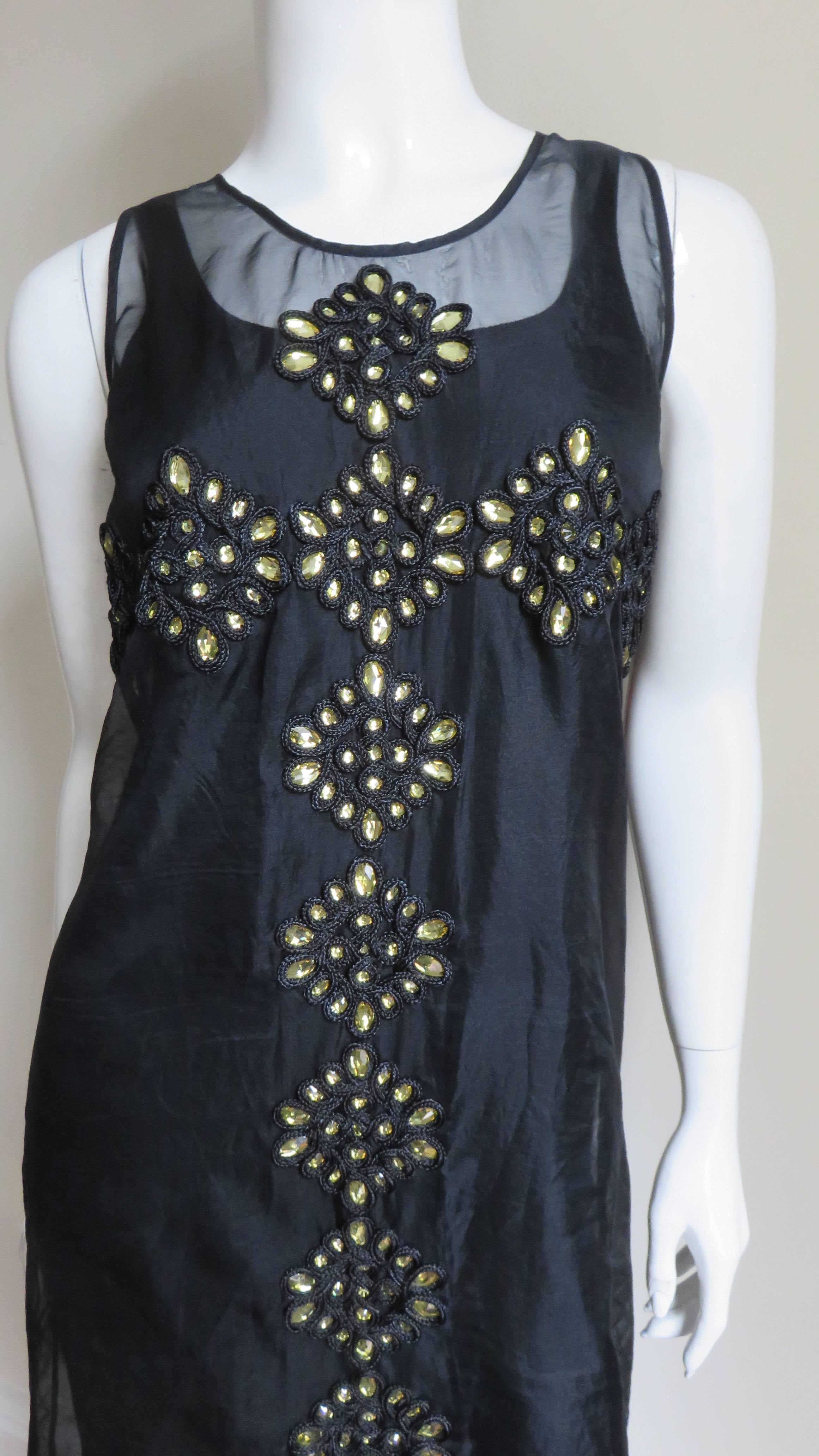 A gorgeous sheer black organza shift dress with large gold beads encased in elaborate embroidery. The dress is sleeveless with a rounded neckline.  Both front and back are adorned with a beautiful pattern of golden beads along the center front and