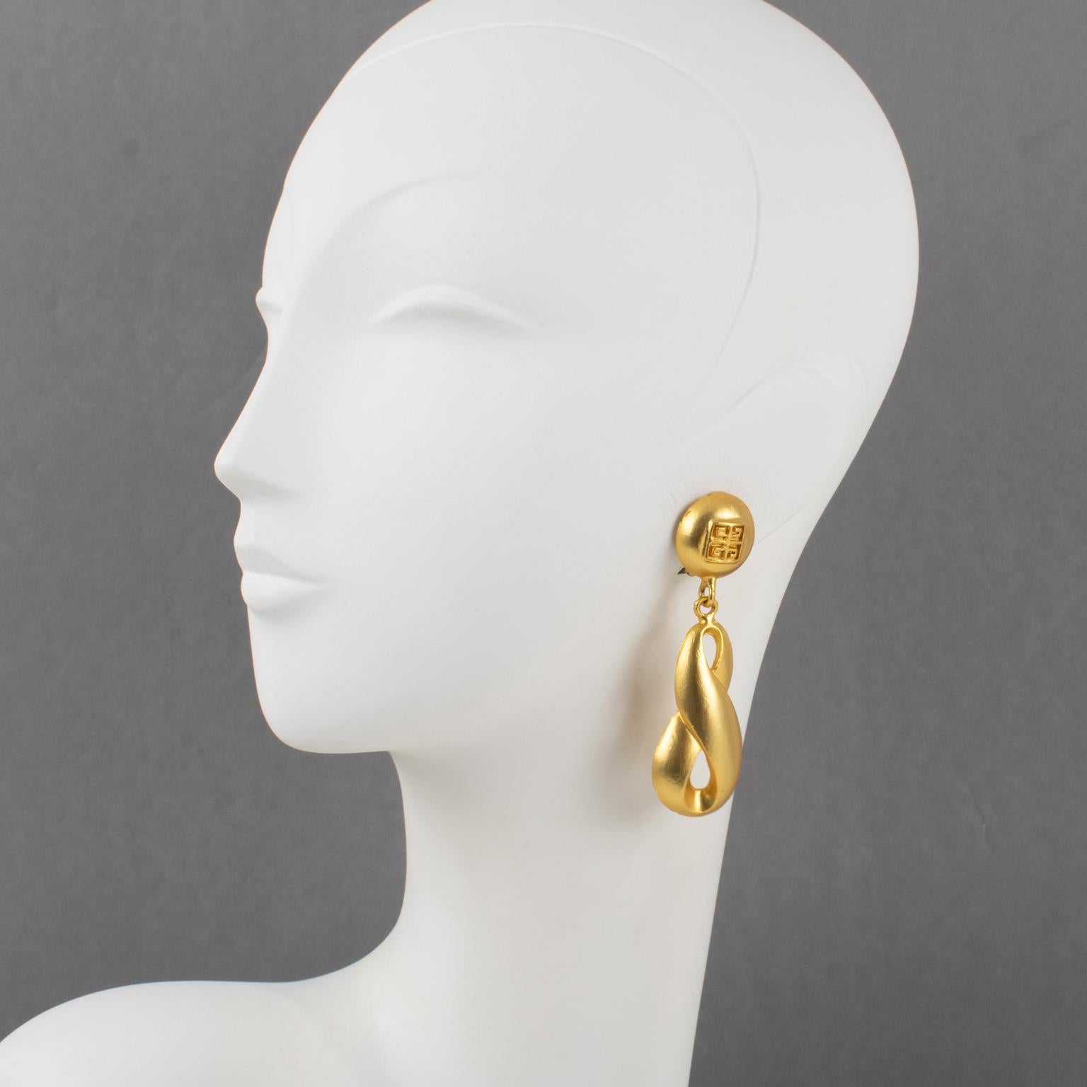 These rare, trendy Givenchy clip-on earrings feature a long, dimensional dangling shape with gilded metal in a satin-finish texture. The front of the earrings is marked with the iconic Givenchy logo.
Measurements: 0.94 in wide (2.3 cm) x 3.19 in