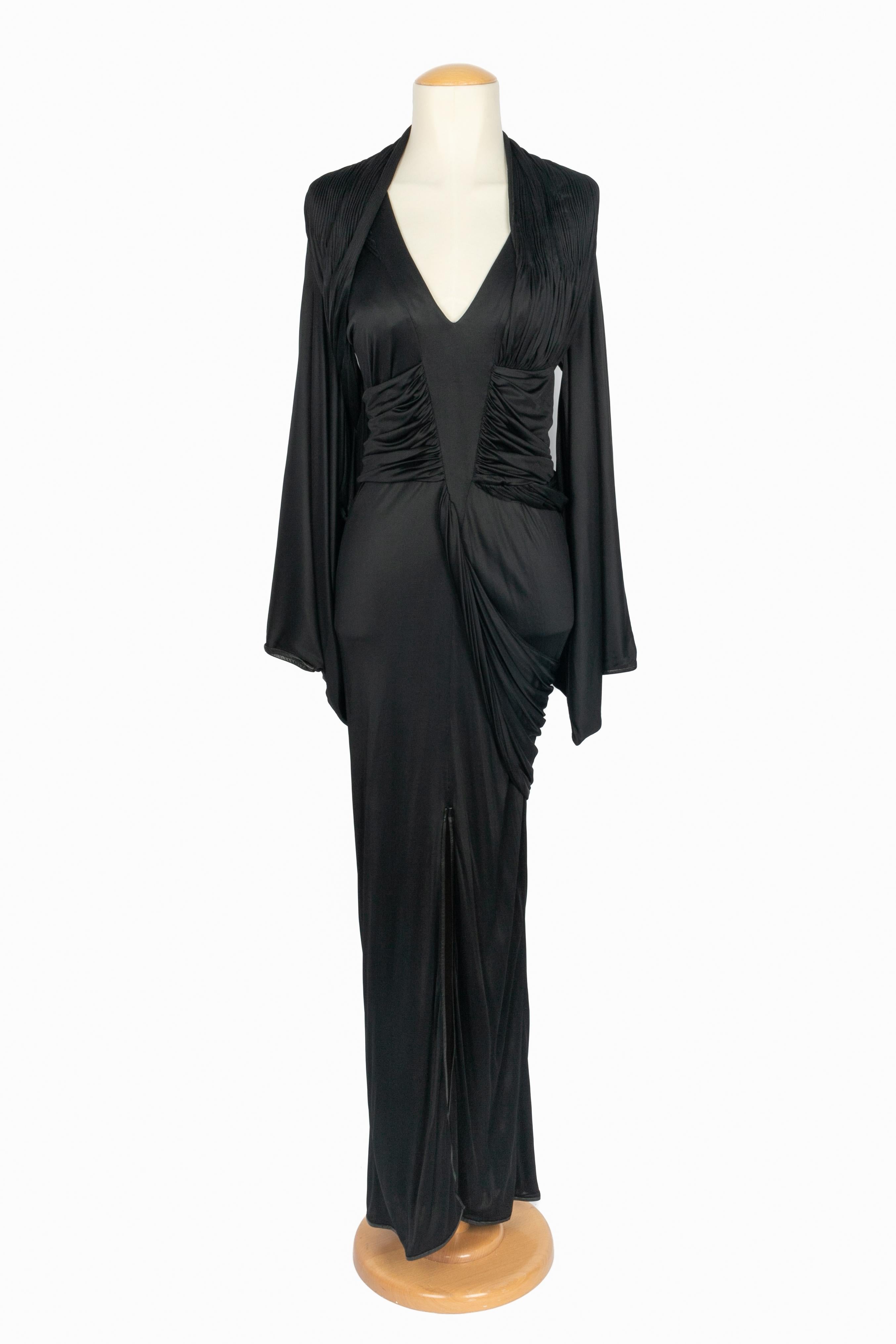 GIVENCHY - Langes schwarzes Viskosekleid mit Schlitz und V-Ausschnitt. Fließende, lange Ärmel, verziert mit Drapierungen und Plissee-Details auf der Vorderseite. Unterteil und Handgelenke des Kleides sind mit einem schwarzen Schrägstreifen aus