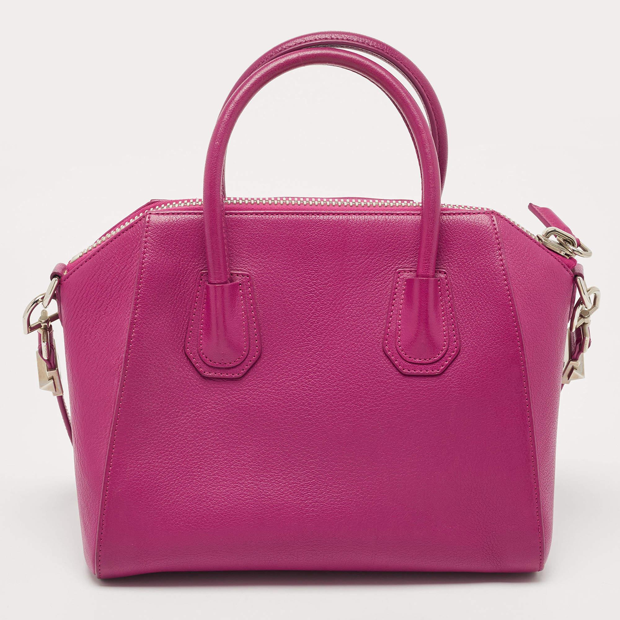 Defined and sturdy, this Givenchy Antigona satchel is one statement bag that will surely hold its value. Crafted from magenta leather, it features an elegant geometric cut, double rolled top handles, a removable shoulder strap, and silver-tone