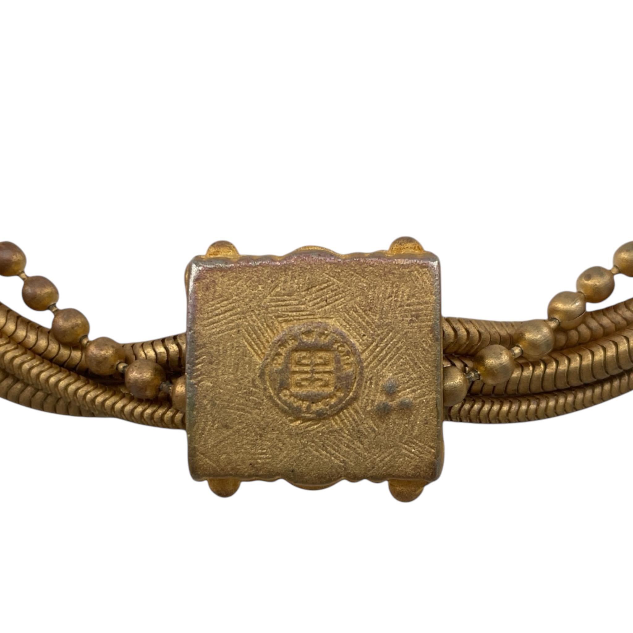 Collier chic en or mat de Givenchy, circa 1990's. Des cristaux rouges et clairs de taille carrée sont sertis dans un pendentif en forme de demi-tonneau. Quatre chaînes. Trois d'entre elles sont des chaînes de serpent de taille variable, et la