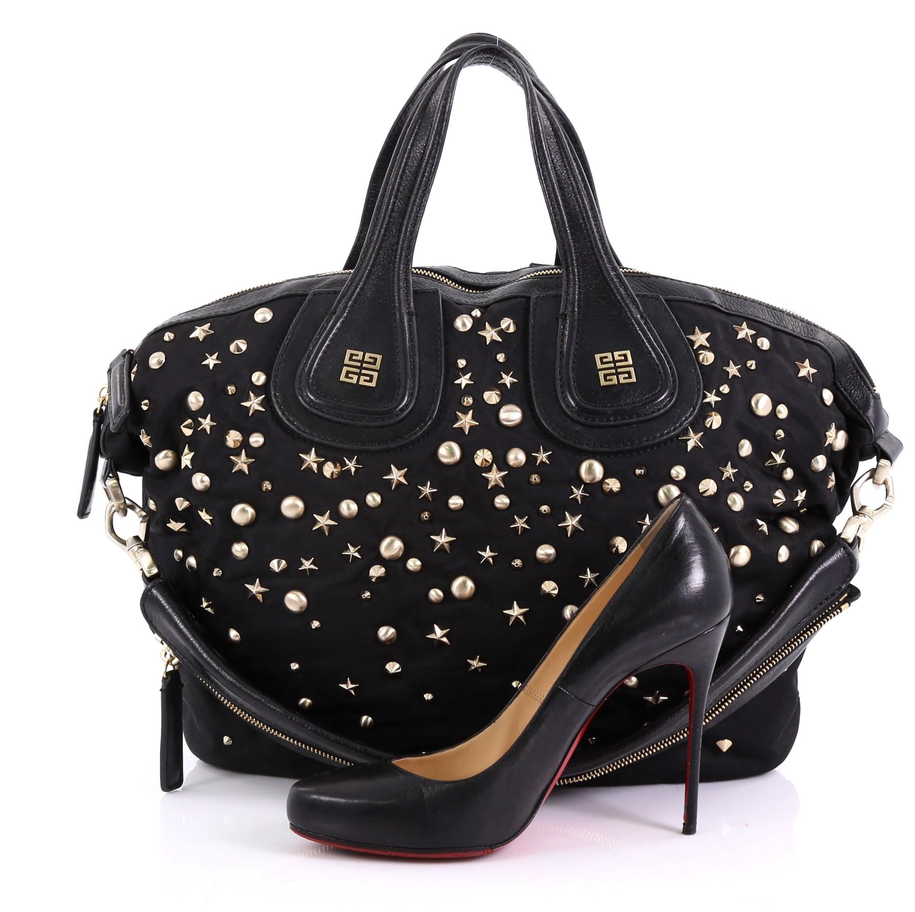 This Givenchy Nightingale Satchel Studded Nylon Medium, crafted in black nylon, features multiple stud details, dual top handles with embossed Givenchy logo emblem, and gold-tone hardware. Its zip closure opens to a black fabric interior with slip