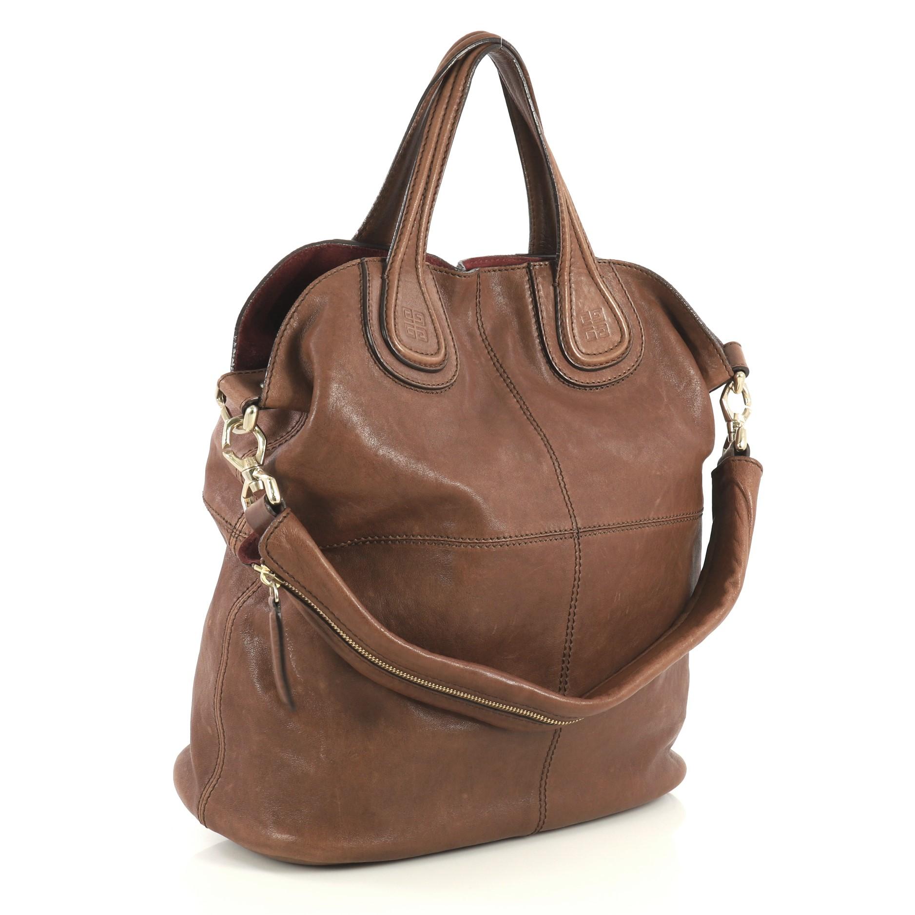This Givenchy Nightingale Tote Leather Large, crafted in brown leather, features dual top handles with embossed Givenchy logo, stitched quarters, and gold-tone hardware. Its hidden magnetic closure opens to a black fabric interior with zip and slip