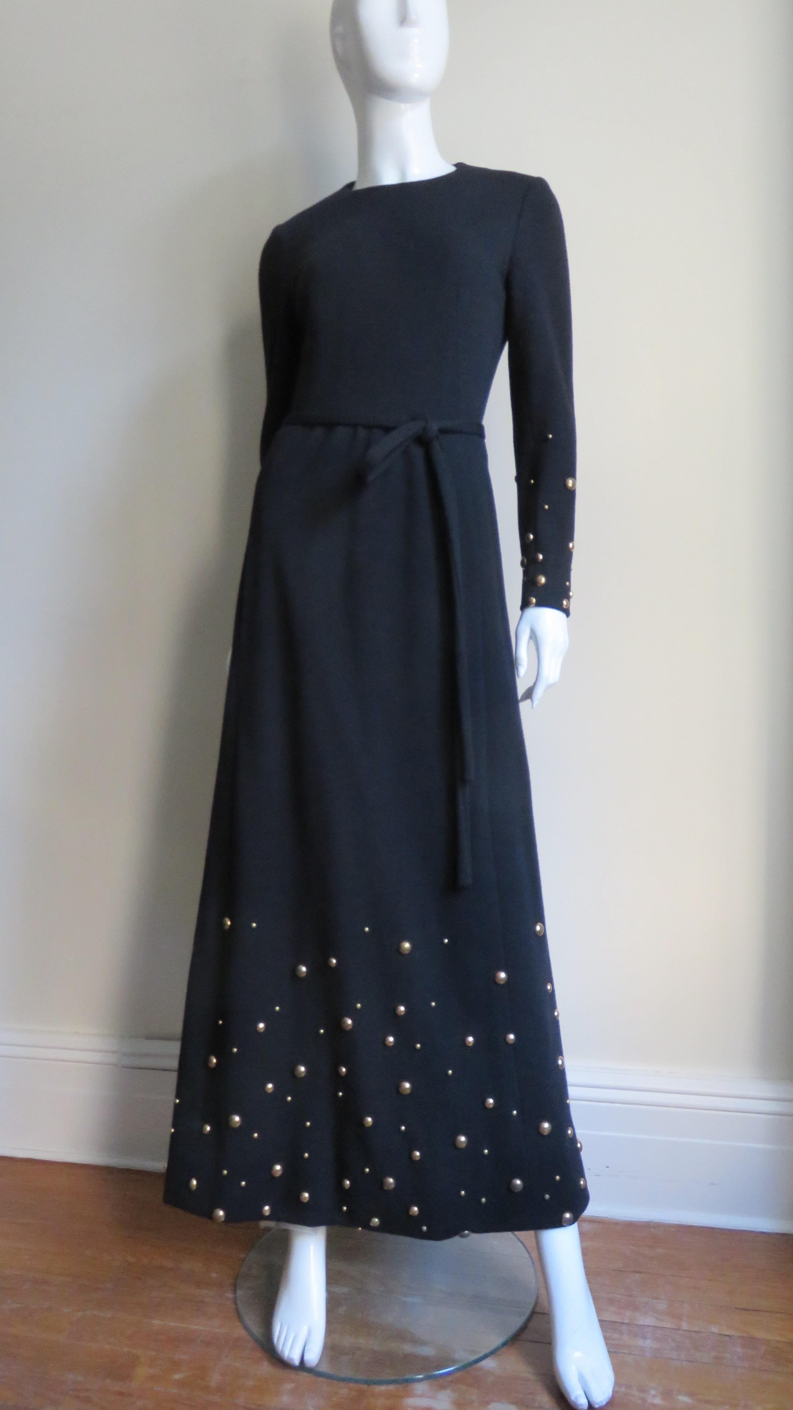 La fabuleuse robe maxi en jersey de laine noir de Givenchy.  Il a des manches longues, une encolure ras du cou et est accompagné d'une étroite ceinture à nouer et d'un châle assorti.  Le bas des manches et la partie de la jupe, ainsi que l'écharpe