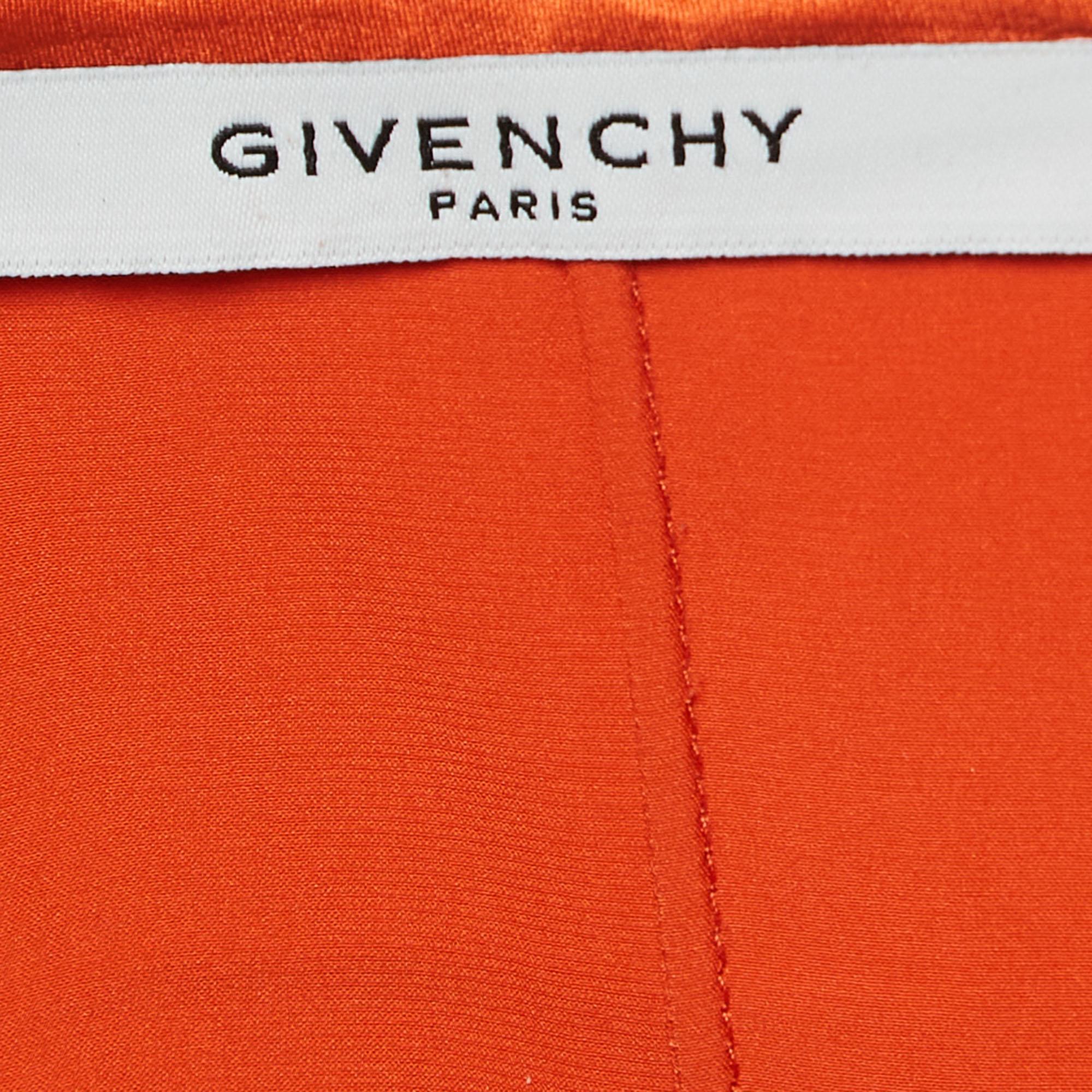 Wrap yourself in elegance with the Givenchy dress. Crafted to perfection, this masterpiece features a vibrant orange hue that captivates the eye. Its sleeveless design and layered silhouette exude modernity and grace. Complete with a chic belted
