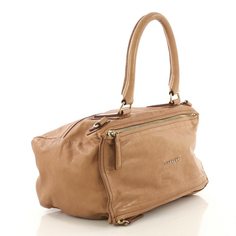 This Givenchy Pandora Bag Leather Medium, crafted from brown leather, features a rolled top handle, exterior zip pocket, and gold-tone hardware. Its two-way zip fastenings open to a neutral fabric interior with side zip and slip pockets. 

Estimated
