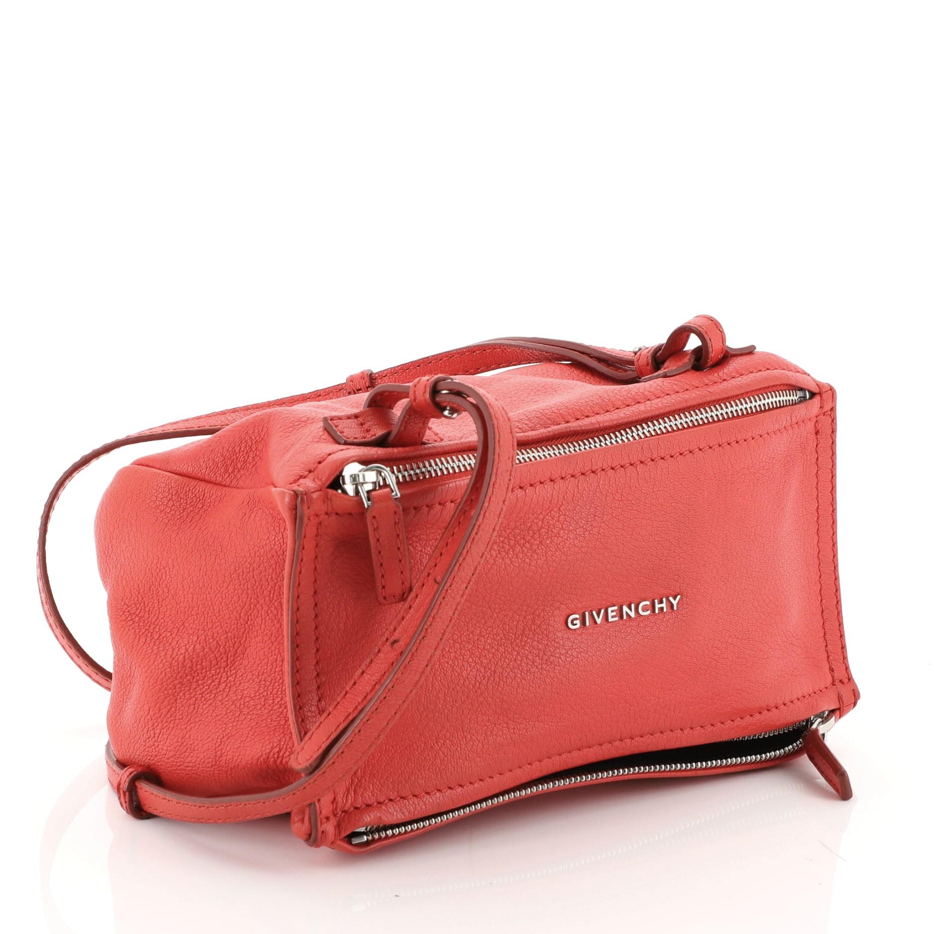 This Givenchy Pandora Bag Leather Mini, crafted in red leather, features an adjustable leather strap, front zip compartment, and silver-tone hardware. Its top zip closure opens to a black fabric interior with side zip pocket. 

Estimated Retail