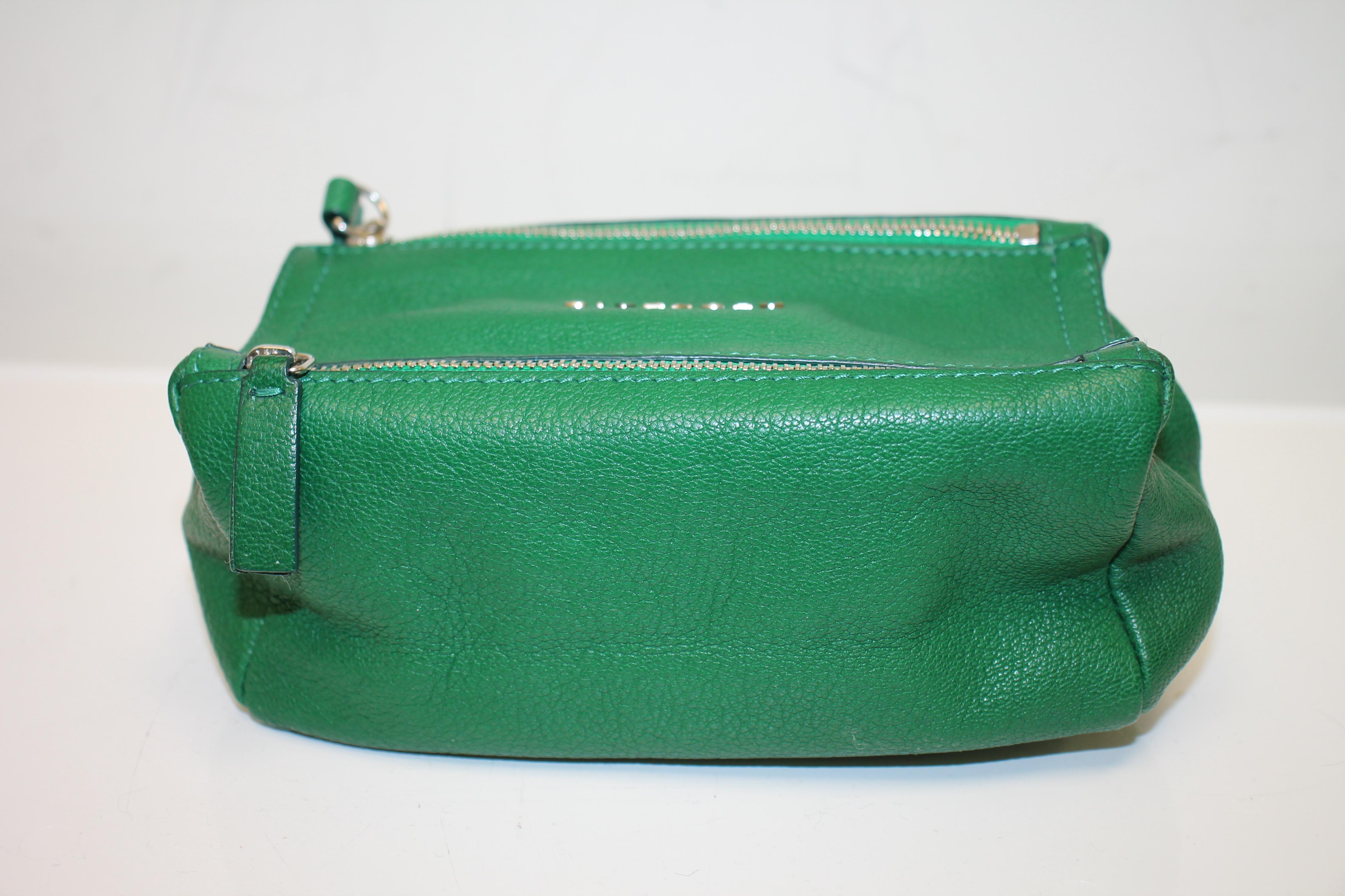 Bright green grained leather. Silver-tone hardware. Zip closure at top. Single flat wrist strap at side with chain-link accents. Logo adornment at front. Single exterior zip pocket at front. Beige canvas lining.