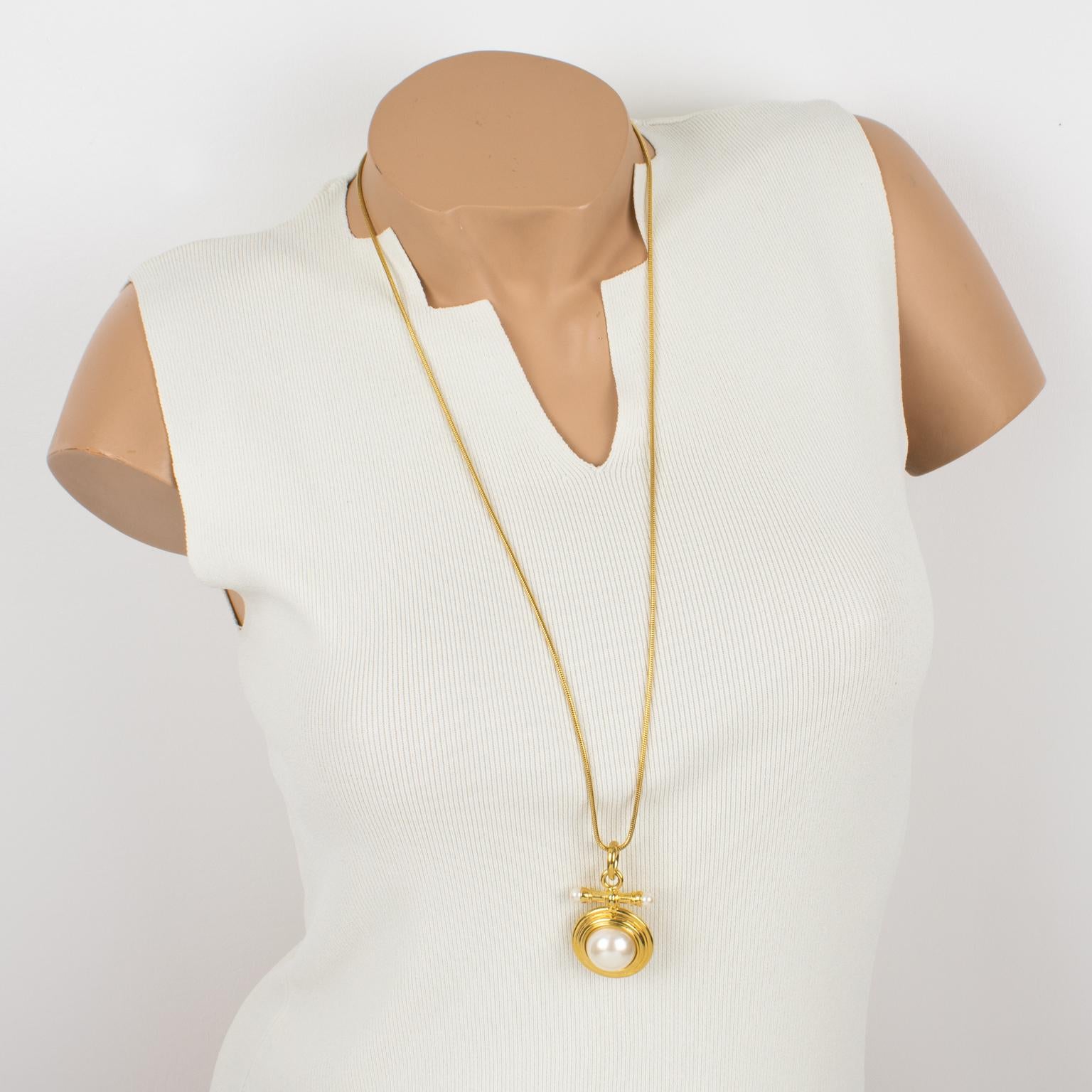 This elegant Givenchy Paris pendant necklace features a dimensional geometric design with shiny gilded metal, complemented by pearl-like cabochons. The long gilt metal serpentine chain has a lobster-closing clasp. The pendant is marked underside