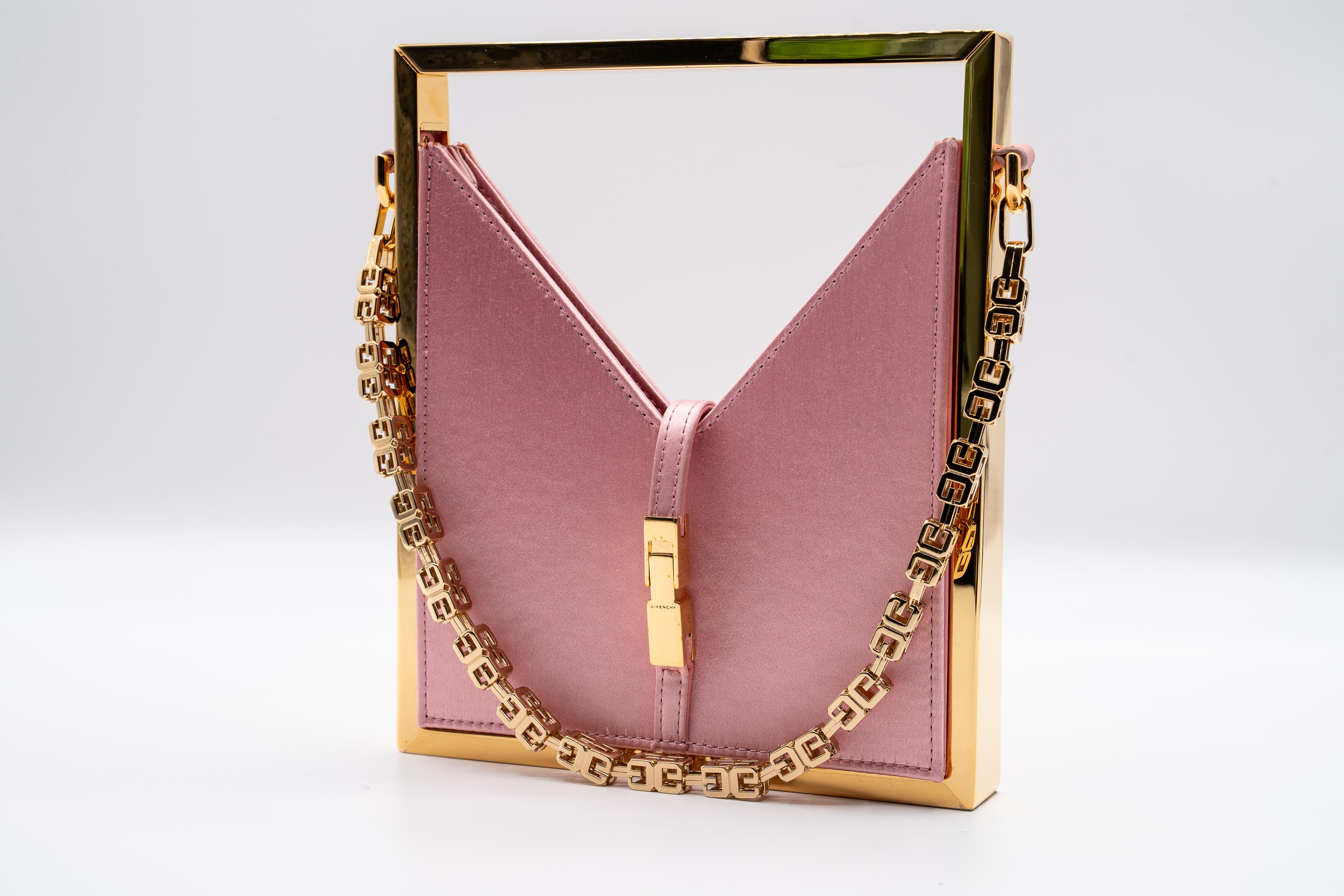 The Givenchy Pink Satin Gold Frame Chain Bag is a stylish statement bag. Made from pink satin, it has a smooth texture and a sturdy gold-tone metal frame. The V-shaped cut-out secures with a gold-tone clasp engraved with the Givenchy logo.

The bag