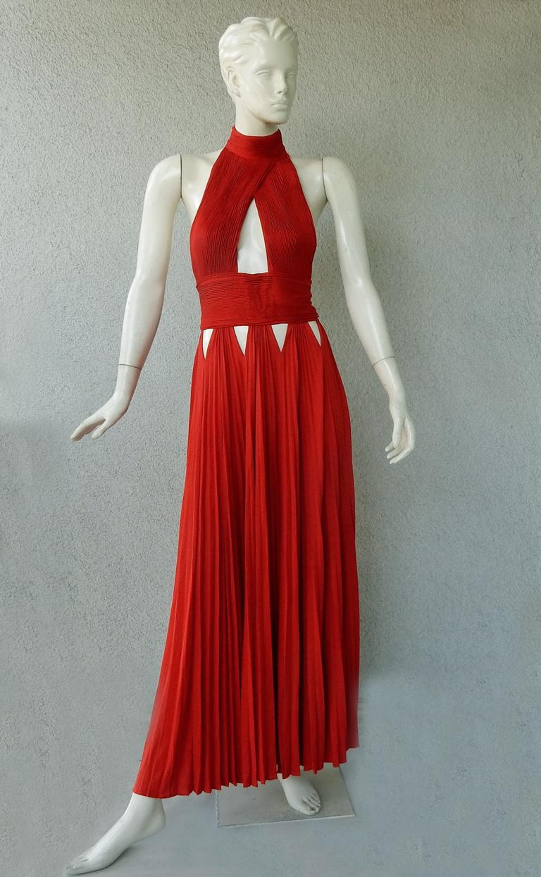 Givenchy red jersey plisse halter evening dress adorned with strategically cut-out panels at hips and bodice.  Pleated skirt drapes easily onto the body.  Open back;  back zipper closure; button neck closure.  Dress has great visual appeal and