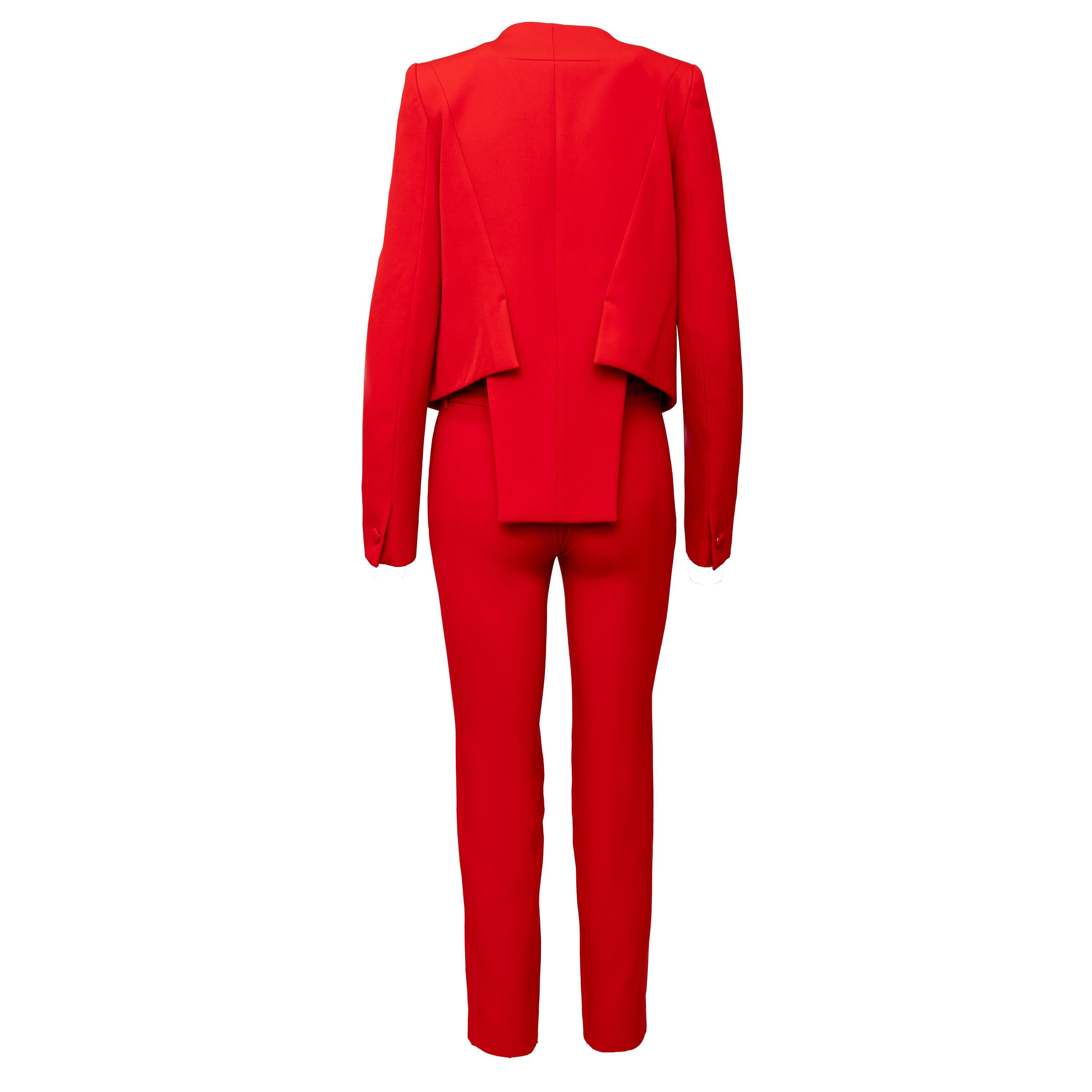 Sapientemente confezionato con una vestibilità aderente, questo abito rosso di Givenchy è un pezzo forte in lana rossa vibrante. La giacca cropped in stile frac è caratterizzata da un esclusivo colletto a pieghe e da padiglioni, mentre i pantaloni