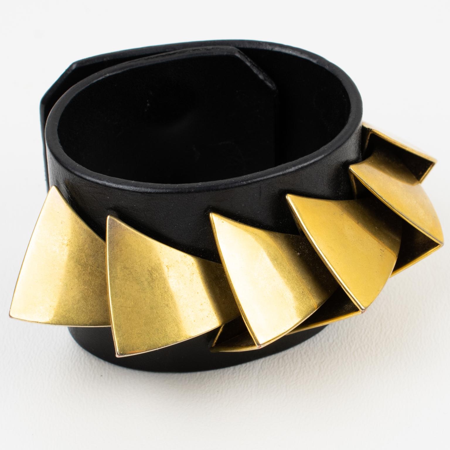 This stylish Givenchy Paris signed belt bracelet was designed by Riccardo Tisci for his 2011 Obsedia Collection. The piece features an oversized band shape in black leather ornate with brutalist geometric gilded brass metal dimensional elements. The