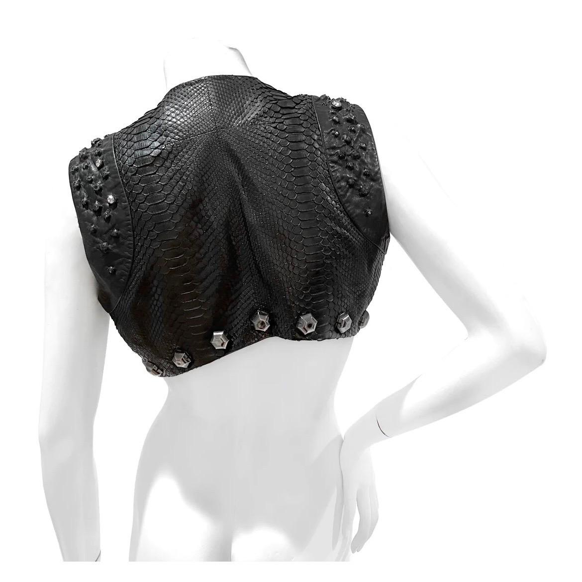 Snake Studded Crystal Embellished Mini Vest by Givenchy
Black
Mini vest style
Snake skin
Large stud and crystal embellishment
Front of vest is longer than the back 
Snake leather
Great Condition; Preloved with slight weathering on the leather. Wear