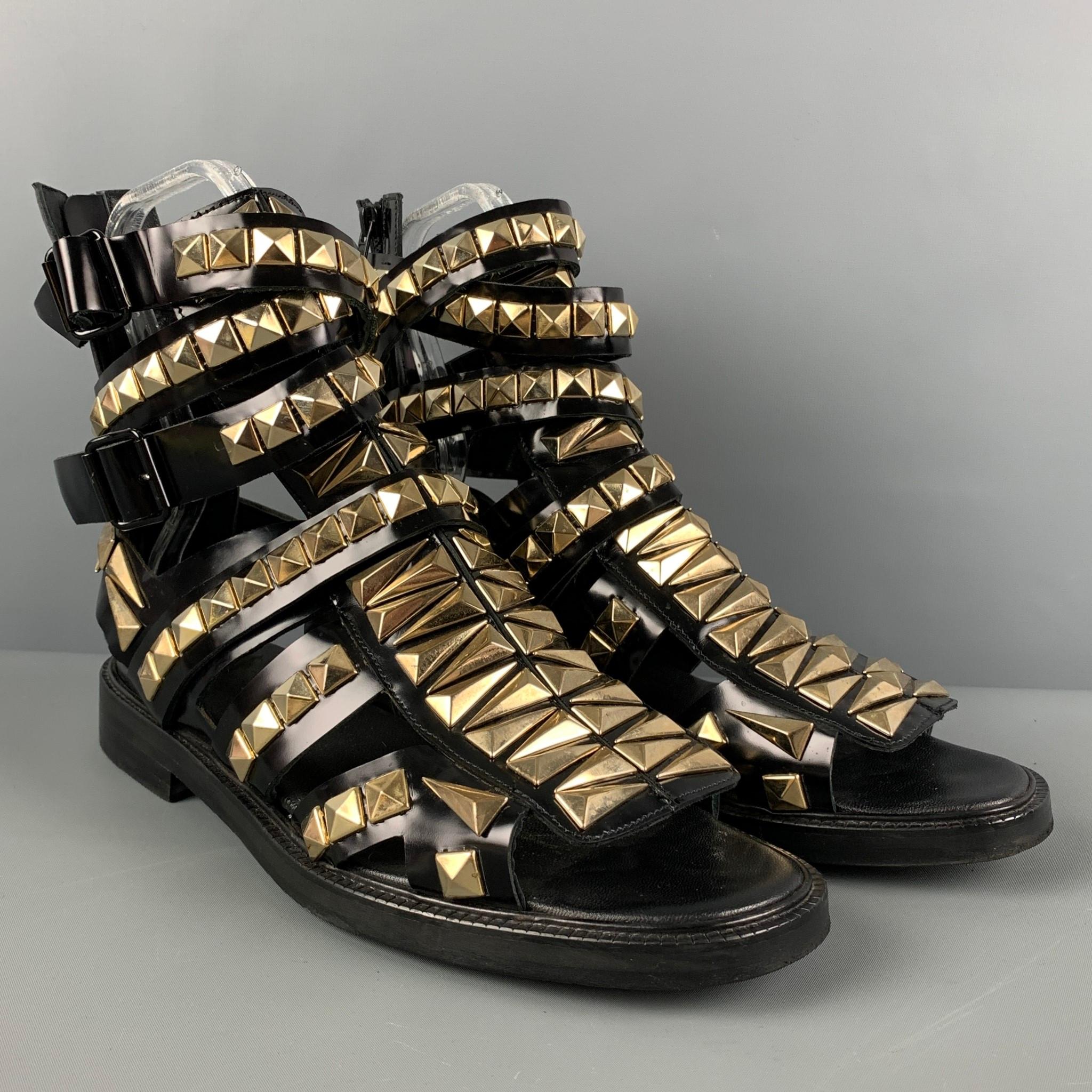 GIVENCHY SS2010 sandals comes in a black leather featuring a gladiator style, gold tone studded details throughout, and a wrap around ankle strap closure. Made in Italy. 

Very Good Pre-Owned Condition.
Marked: 44

Outsole: 12 in. x 4.5 in.