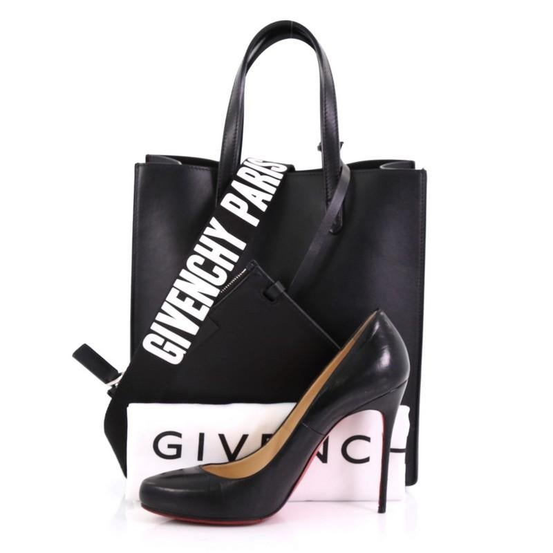 This Givenchy Stargate Shopper Tote Leather Medium, crafted from black leather, features dual slim handles and silver-tone hardware. Its wide open top showcases a black microfiber interior. **Note: Shoe photographed is used as a sizing reference,