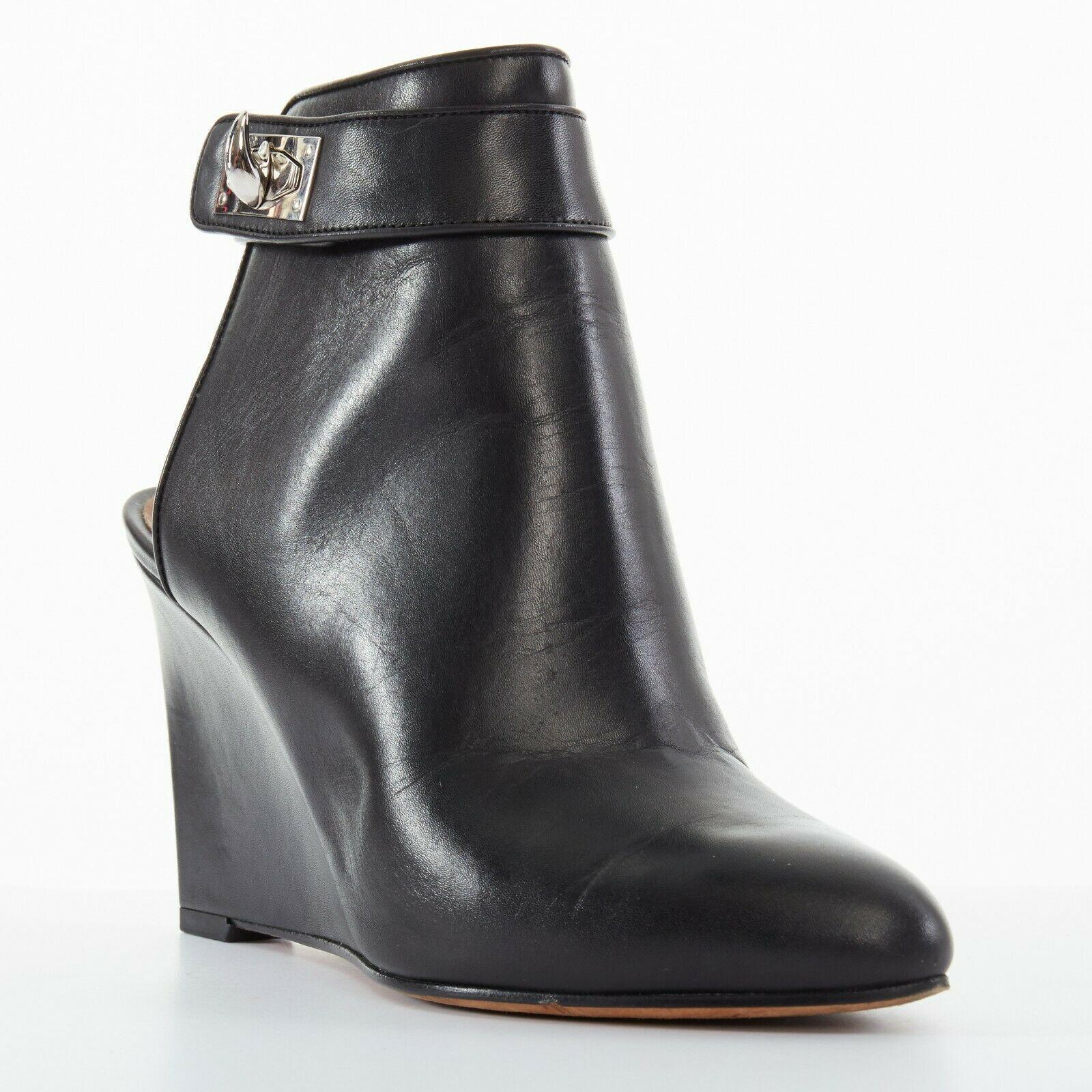 GIVENCHY TISCI black leather sharktooth turn lock mule ankle bootie wedge EU37.5
GIVENCHY BY RICCARDO TISCI
Black leather upper. 
Rounded pointy toe. 
Leather covered wedge heel. 
Attached ankle strap. 
Silver-tone hardware. 
Shark tooth turn lock