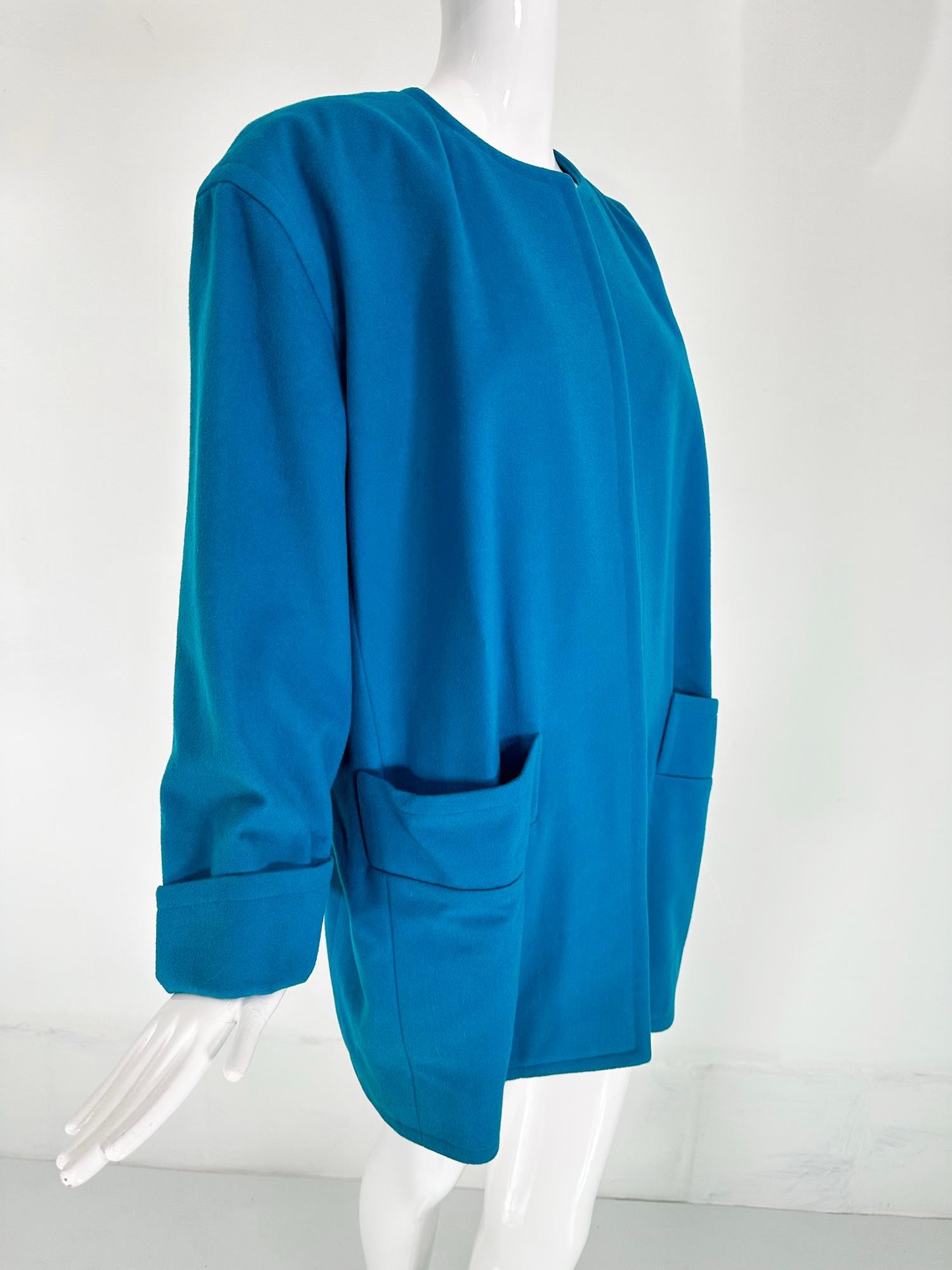 Givenchy turquoise wool open front swing coat with banded angled hip front pockets from the 1980s. Round neck coat is open at the front, dropped shoulders with  long full sleeves and turn back cuffs. The coat can be worn belted for a sleek look or
