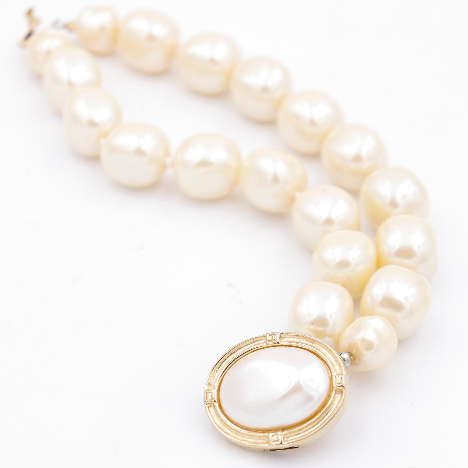This vintage Givenchy baroque style faux pearl bracelet is such a great statement piece! This gorgeous bracelet features large irregular shaped faux pearls and a gold plated clasp with a center large oval pearl. The metal around the center is neatly