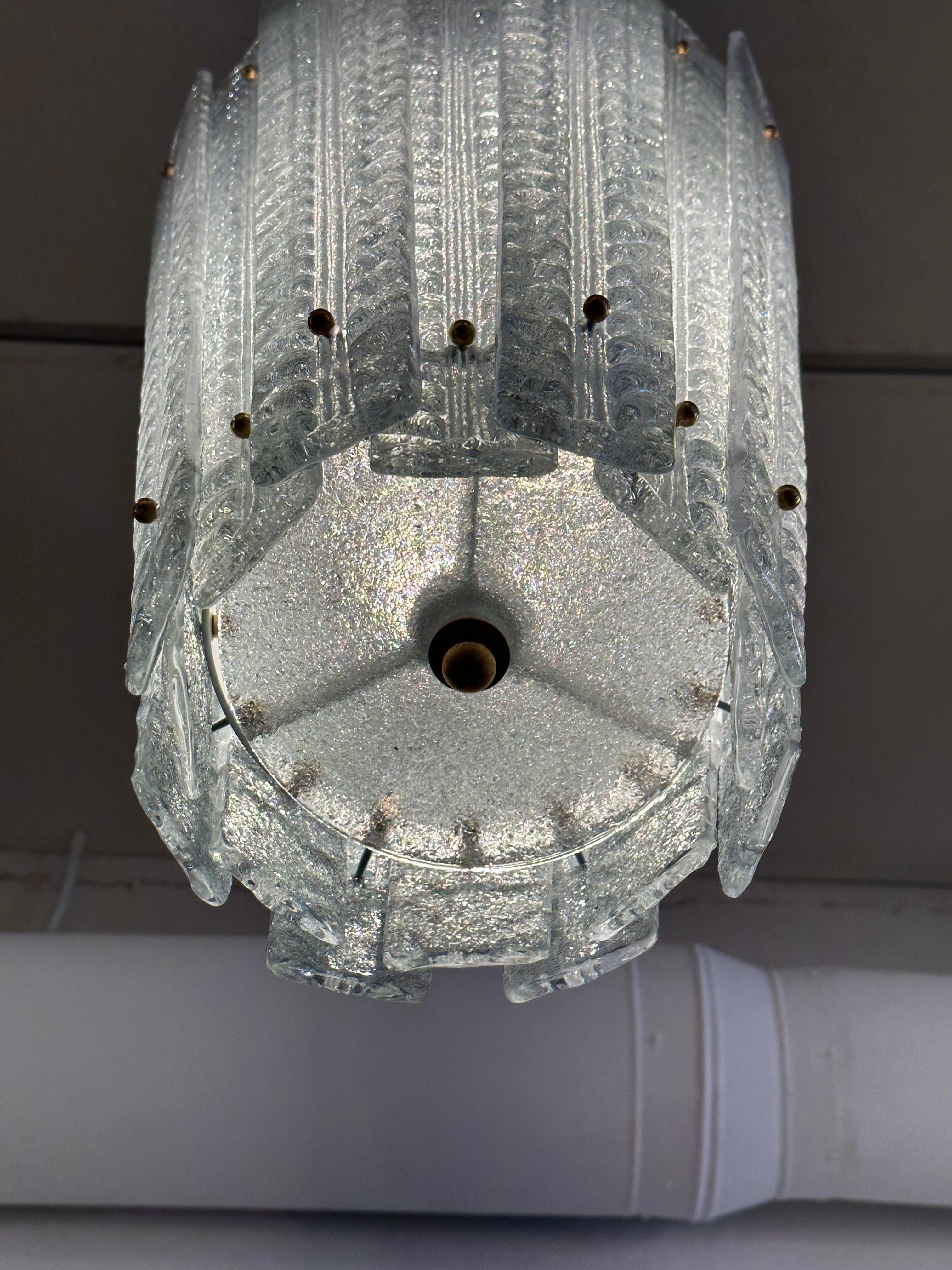 Questo lampadario in stile lanterna con pannelli blu ghiacciaio dal design geometrico e moderno è dotato di un'asta centrale in ottone e di un baldacchino che può essere accorciato se necessario per soddisfare le tue esigenze di design.  Ne sono