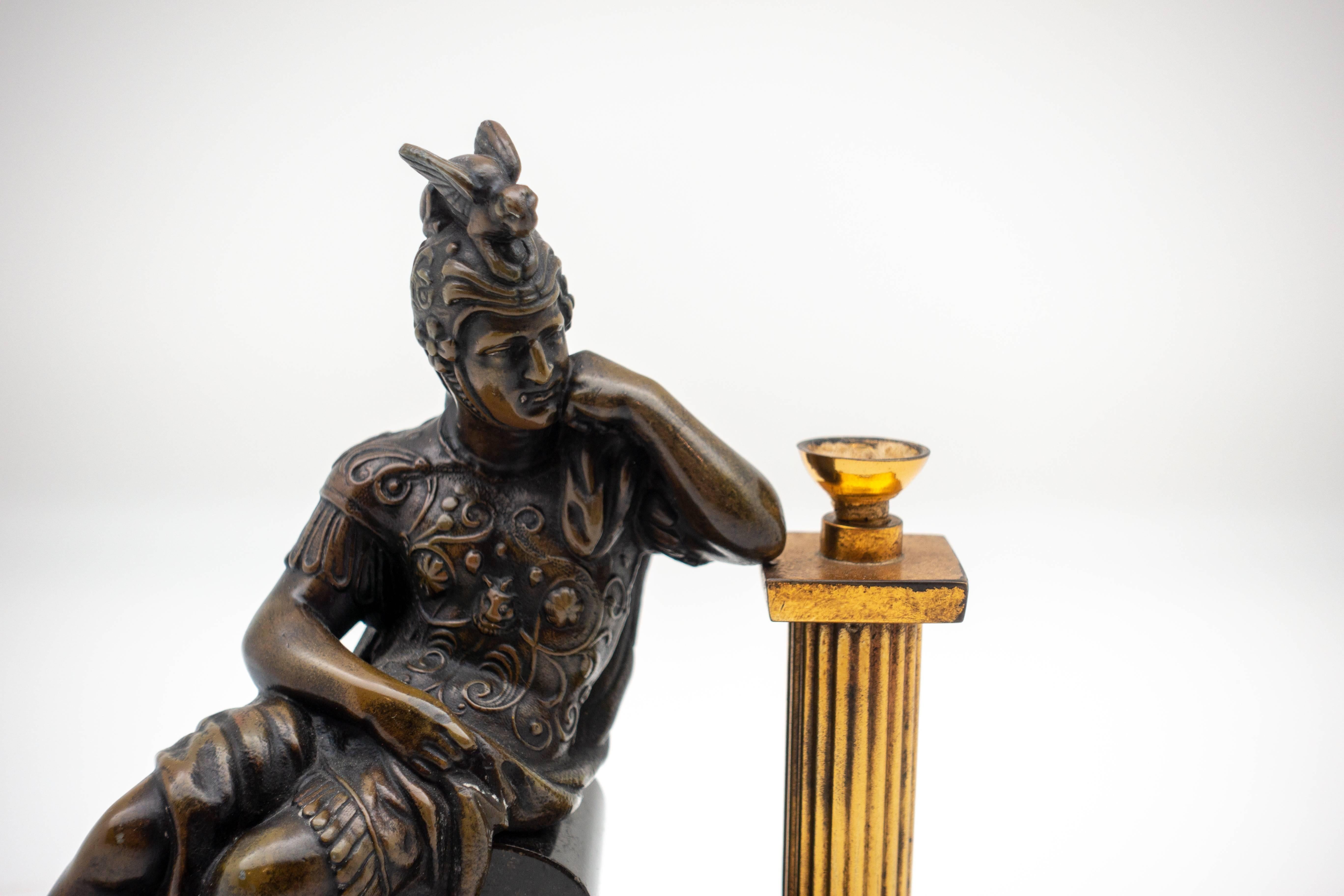 A figural cigar lighter modeled as a gladiator warrior leaning on a column which holds the wick, patinated bronze over metal and mounted on a black marble base, very good condition, circa 1900.