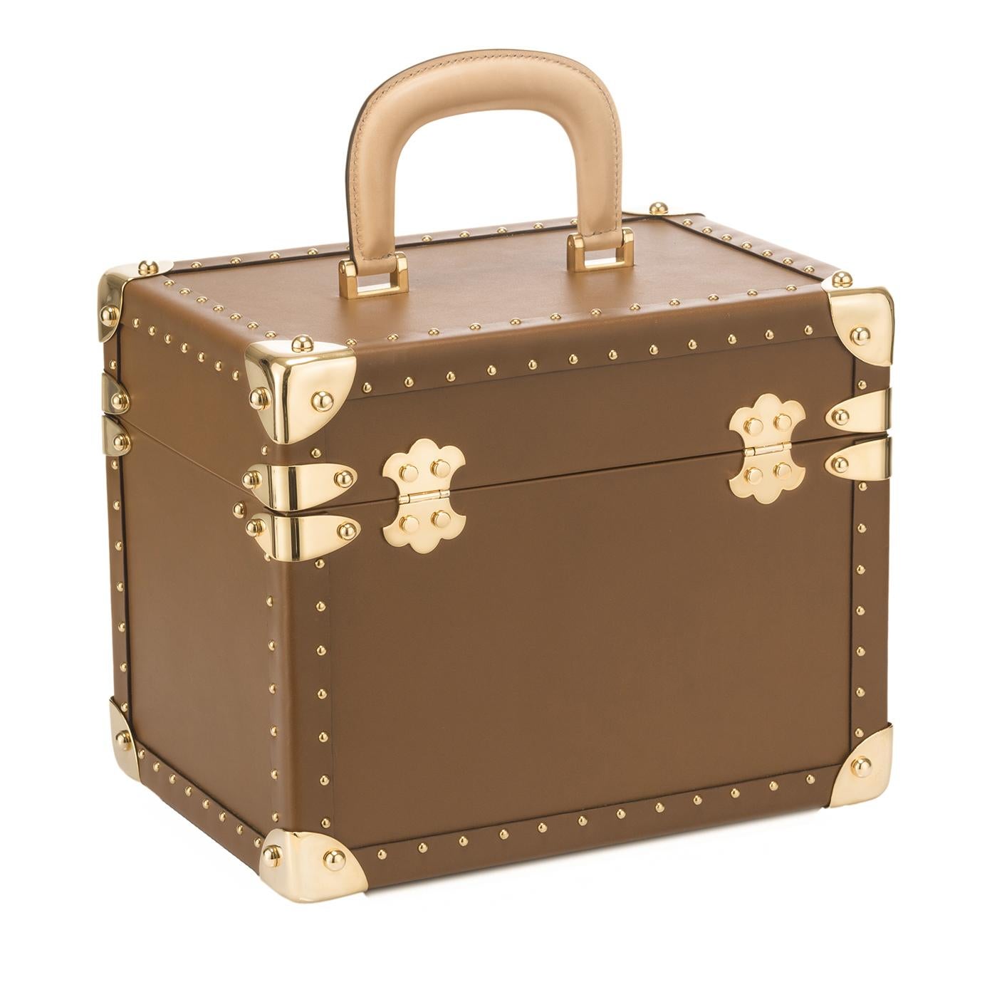 Als Teil der Glam Chic-Kollektion vervollständigt dieser Waschtischkoffer den Look des Glam Chic-Trolleys. Seine quadratische Form ist von den alten Reisetruhen inspiriert. Sein Äußeres ist aus cognacfarbenem Leder. Der Griff ist aus