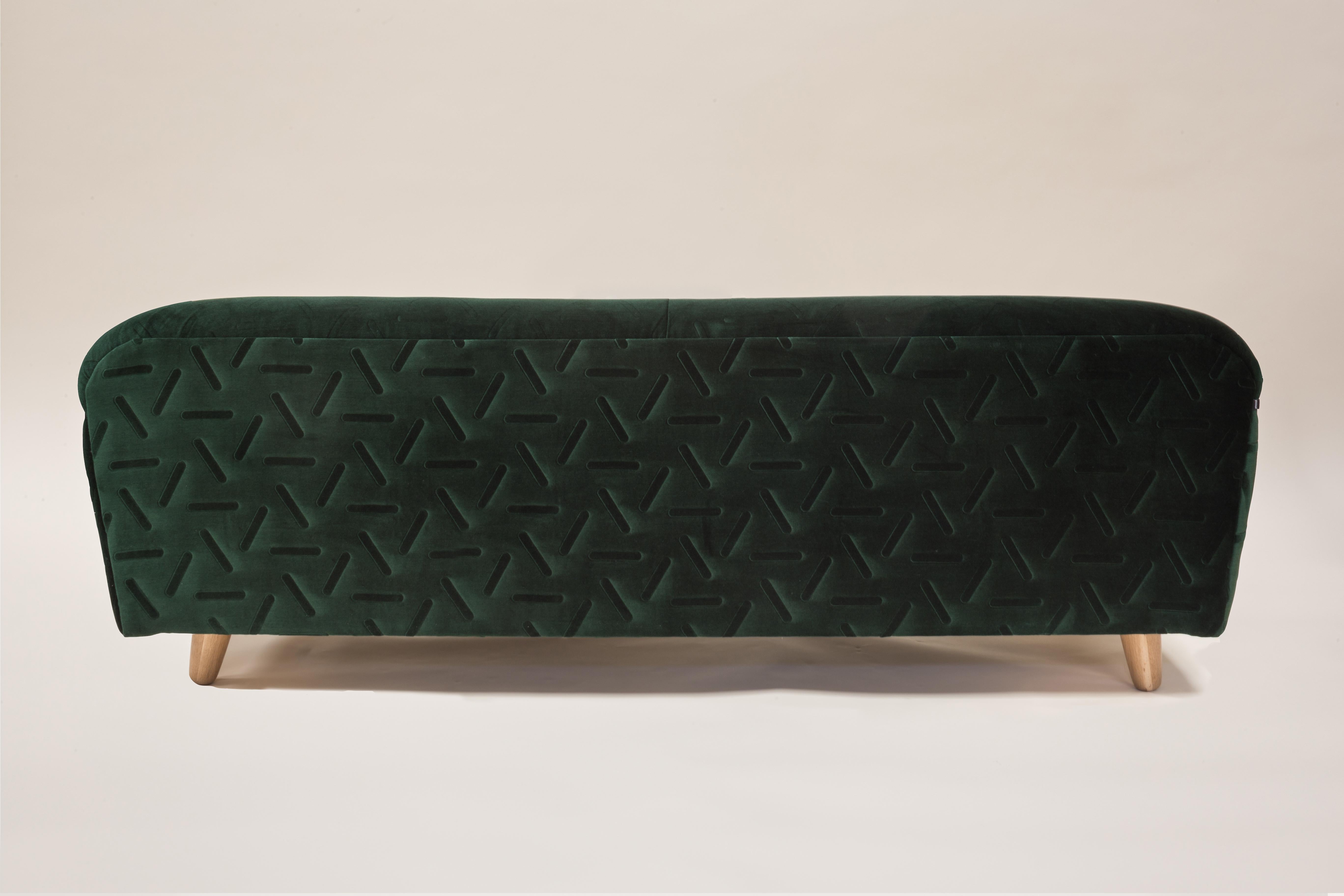 This curvy sofa produces a beautiful silhouette. The embossed velvet fabric contains a geometric pattern and texture on both the cushions and the external covering, giving the sofa an element of understated elegance.