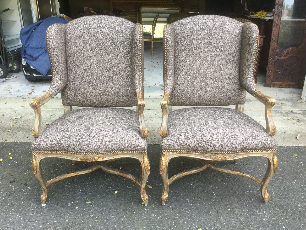 Gorgeous pair of vintage French style painted wingback armchairs upholstered in a soft brown cheetah print, and having carved and gilded frames. There is an elegant cross stretcher for added sturdiness. The custom upholstery is a quality woven print