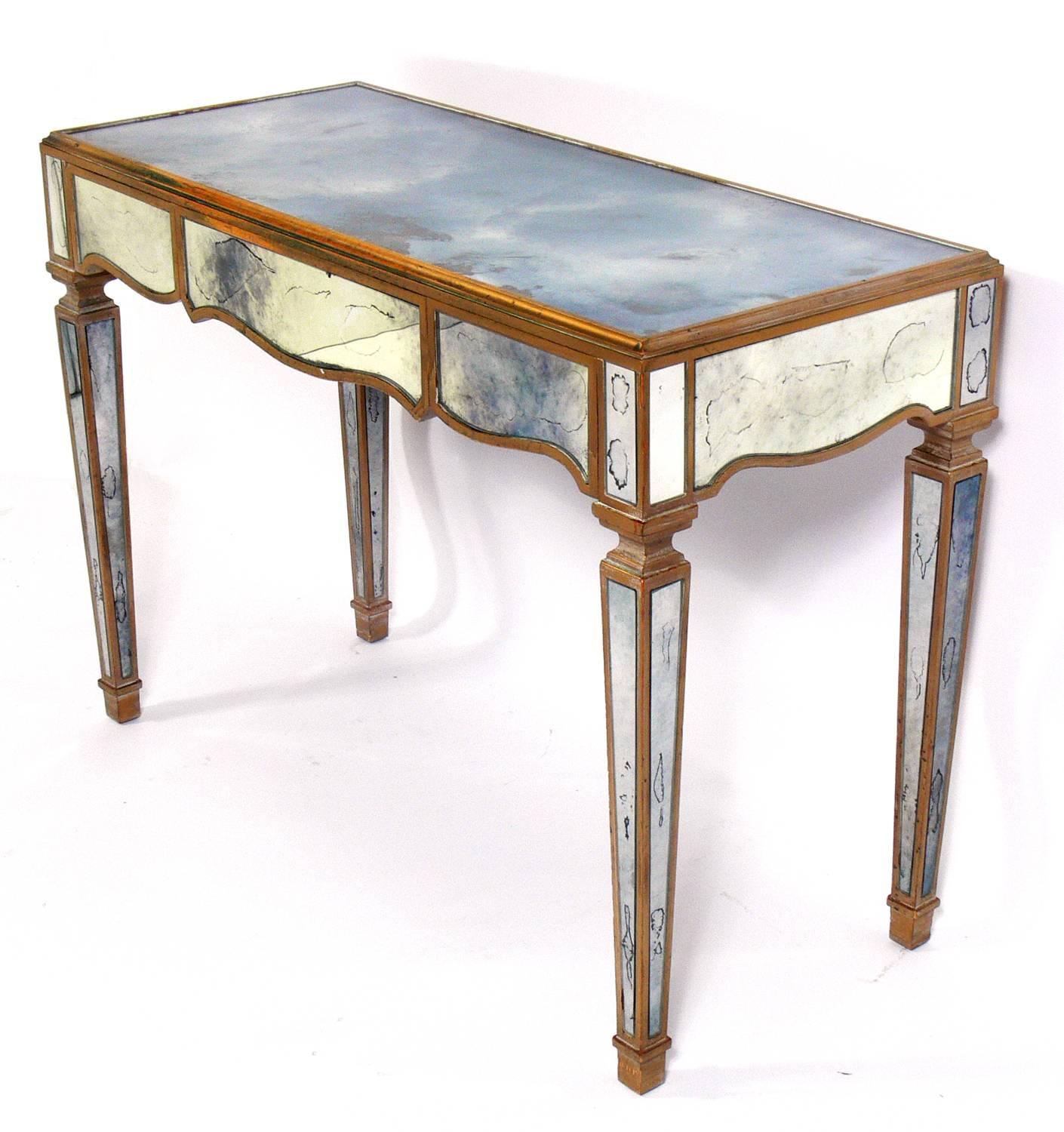 Glamorous mirrored vanity and mirror, American, circa 1940s. This piece is a versatile size and can be used as a vanity, desk, bar, or console table. It retains it's original distressed patina to the mirrored and painted wood surfaces. The mirror