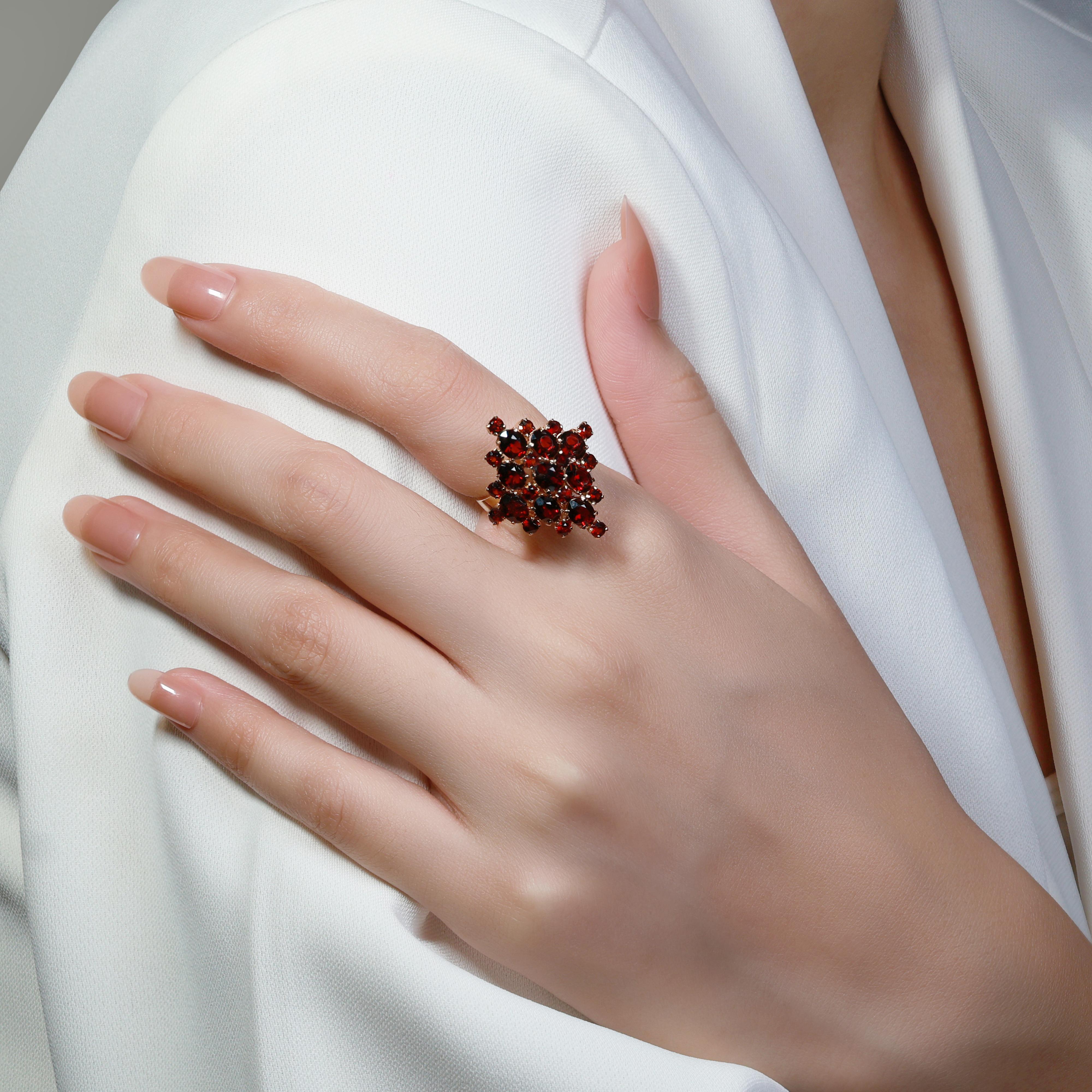 This beautiful piece is crafted from 18K yellow gold and features nine stunning oval garnets as the main stones, totaling 4.50ct, each showcasing a vibrant red color. Accompanying these are 16 round brilliant garnets as side stones, weighing a