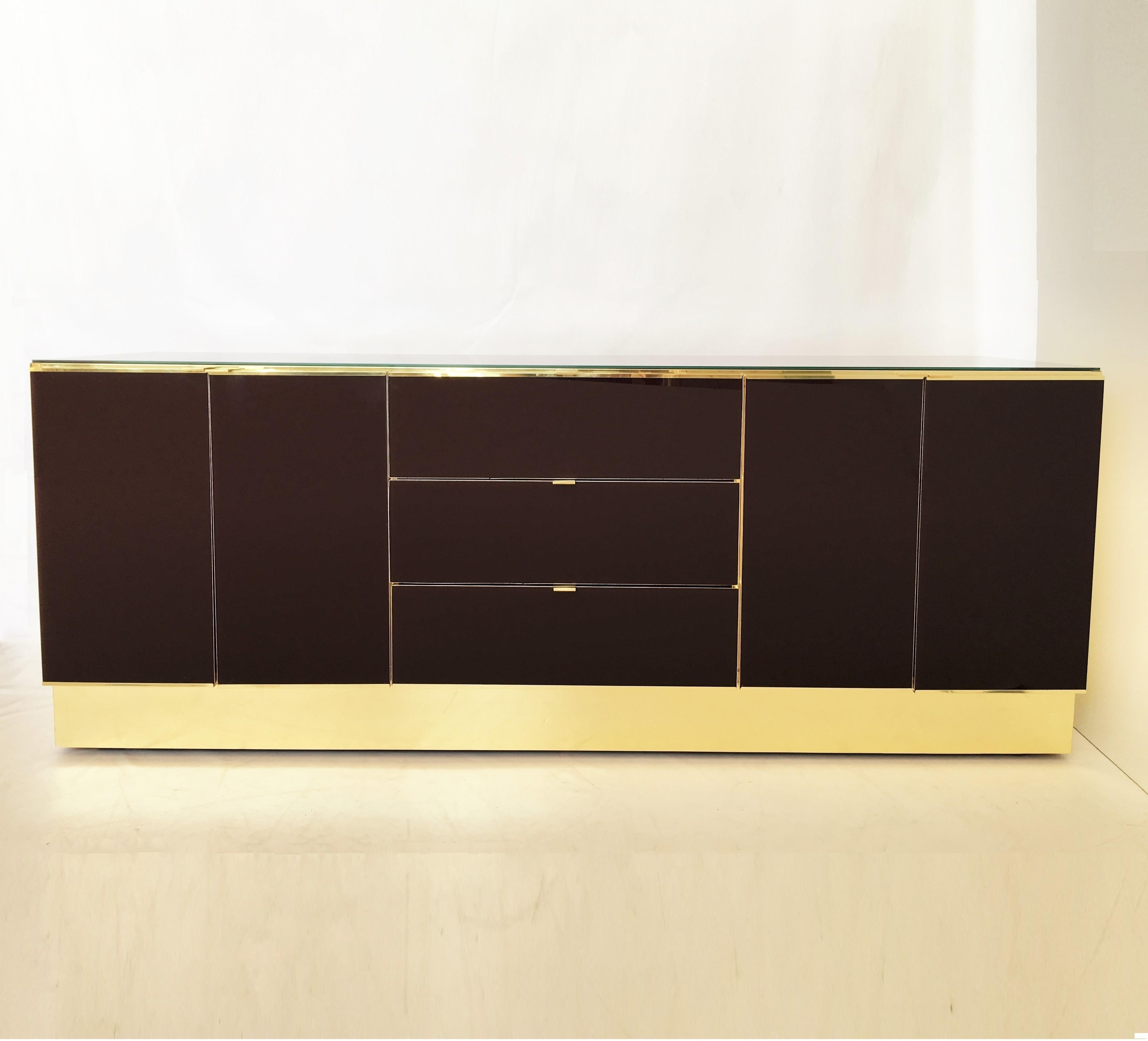 This spectacular dresser is clad in brass and painted glass by Ello Furniture. The burgundy colored glass is absolutely stunning. The dresser and chest feature a panel case, overlaid with mirrored panels, including tab pulls and terminating in a