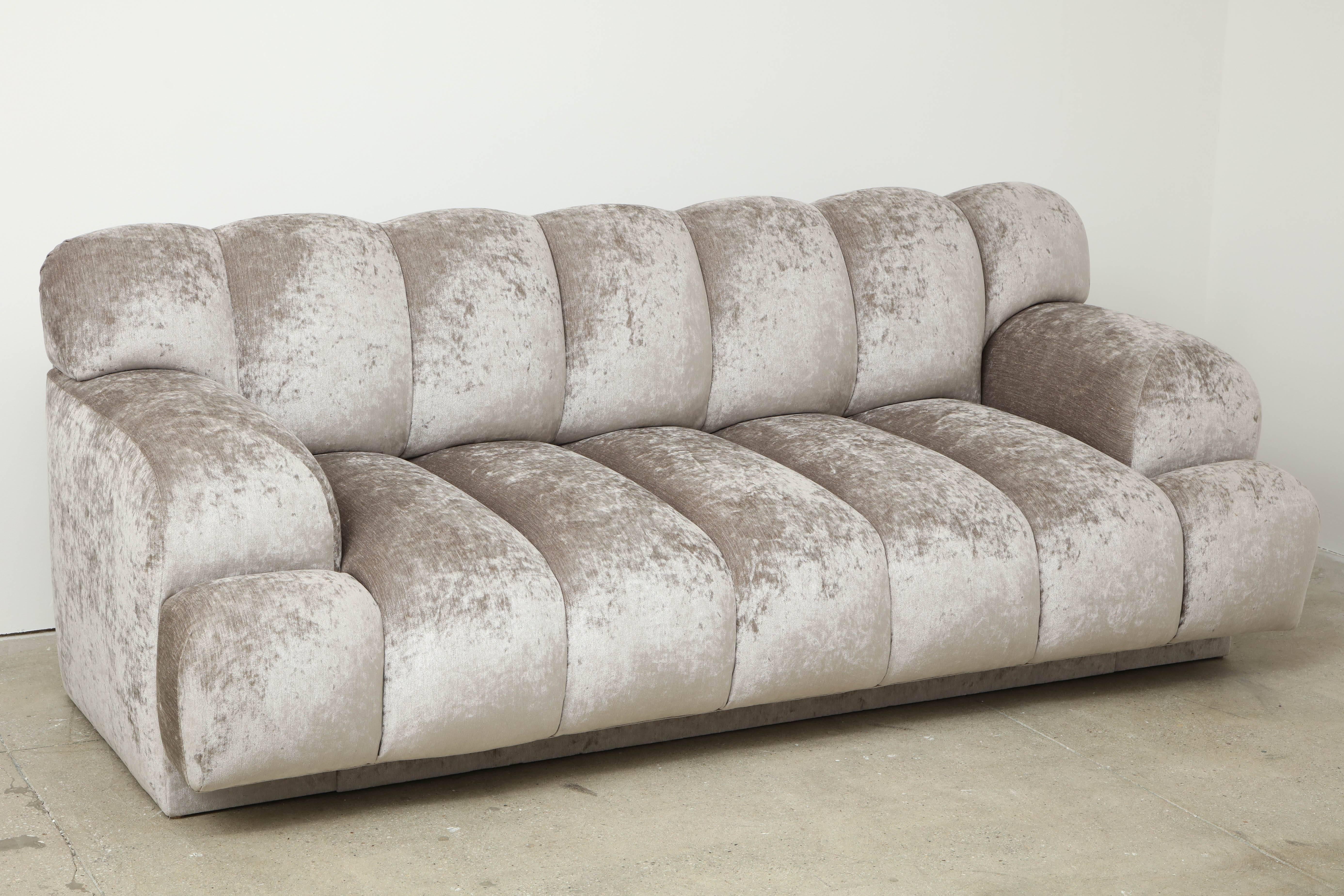 Glamorous channel tufted sofa by Steve Chase.
The chic sofa has been newly reupholstered in a luxurious silvery grey chenille velvet. The sofa is accompanied by two matching pillows.
