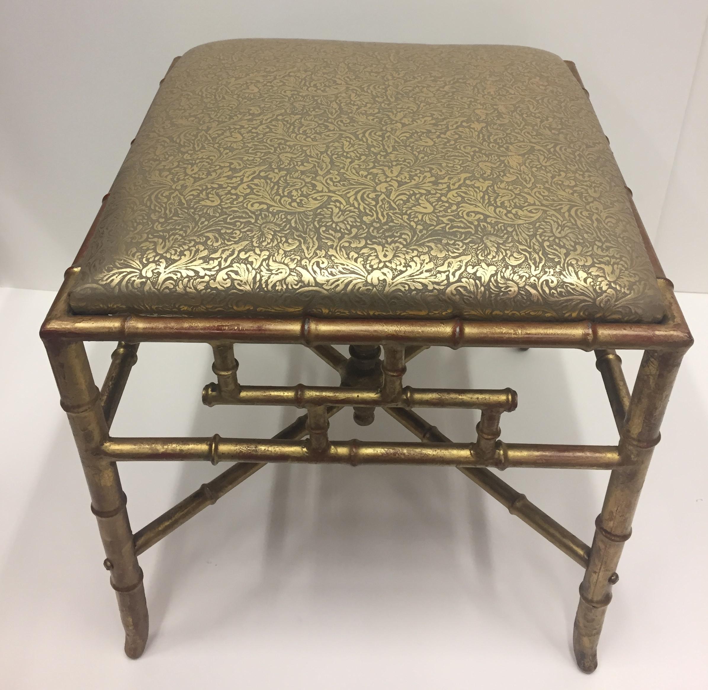 A glitzy and elegant Italian gilded iron ottoman bench having subtle red underpaint on its faux bamboo base and gorgeous new Florentine style embossed gold leather upholstery.
 