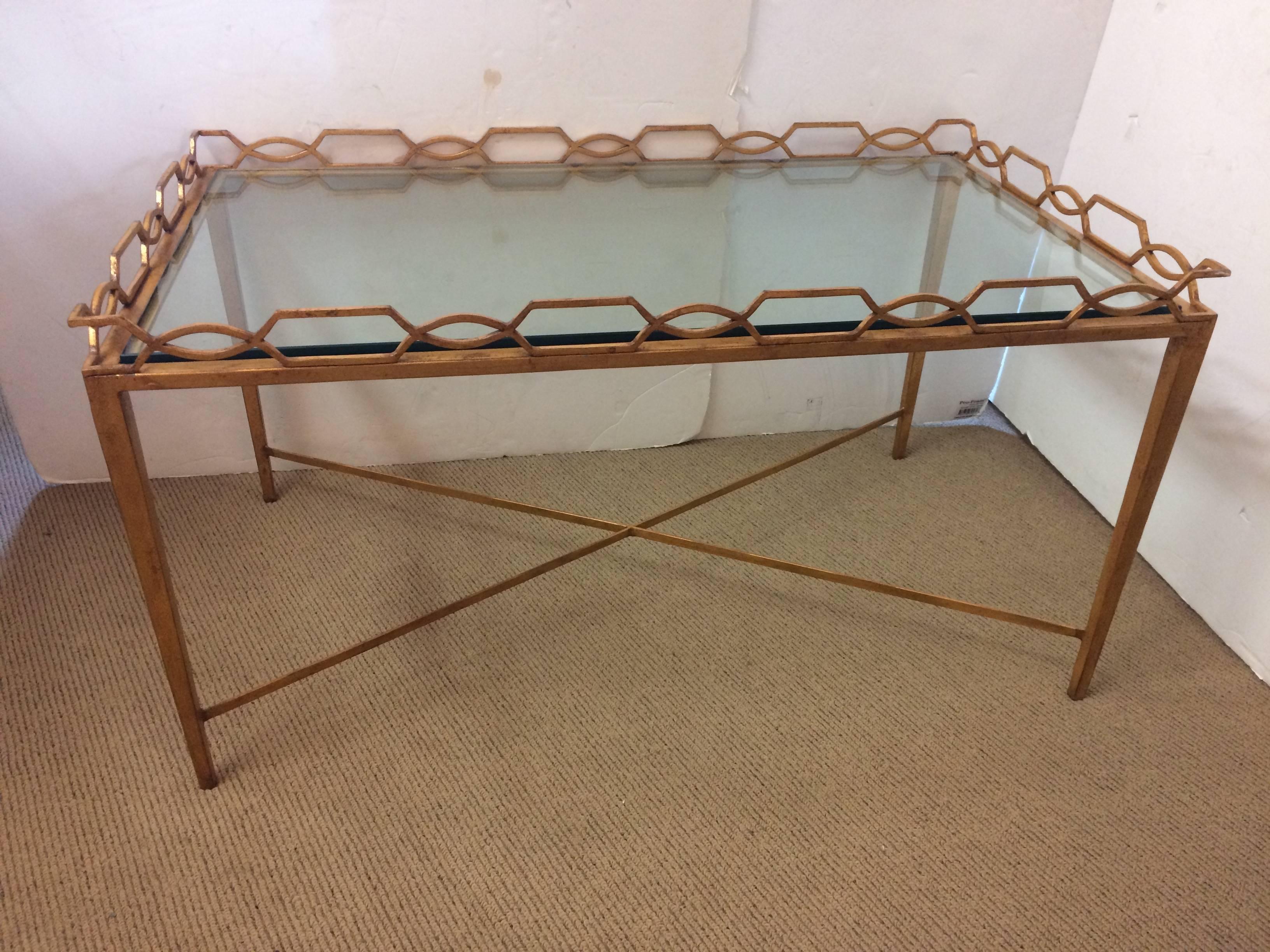 Medium sized rectangular gilt iron coffee table having stylish geometric link gallery around the glass top and elegant tapered legs and stretcher bars.
18.5 inches to top of gallery but surface of glass table is 17 high.