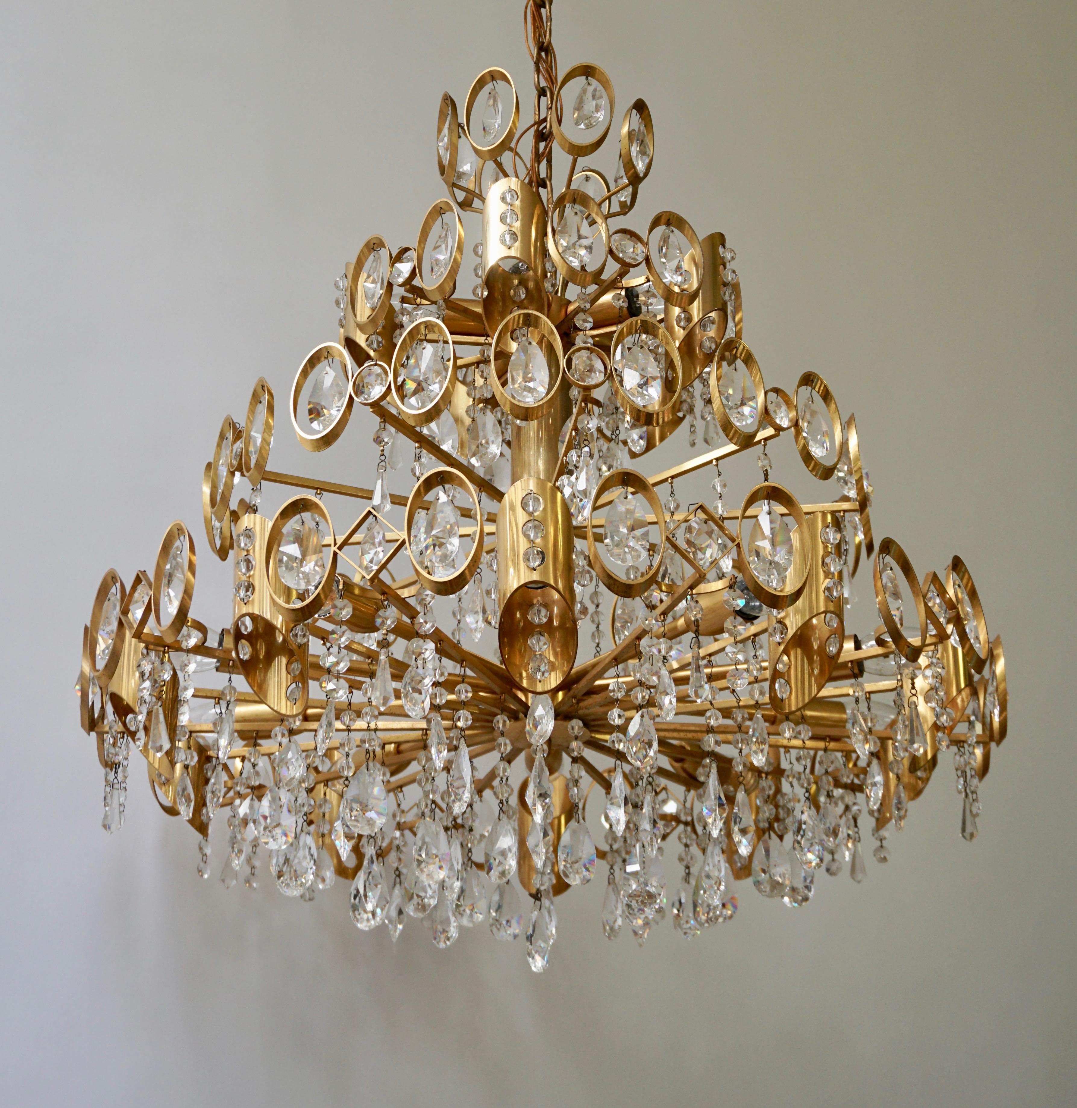 Stunning large Hollywood Regency Palwa chandelier with a gilt brass frame and chain with faceted crystal embellishment suspended within the frame by Palwa.
Fixture has 15 E14 light sources.
Chandelier body measures 27 inches in diameter x 27