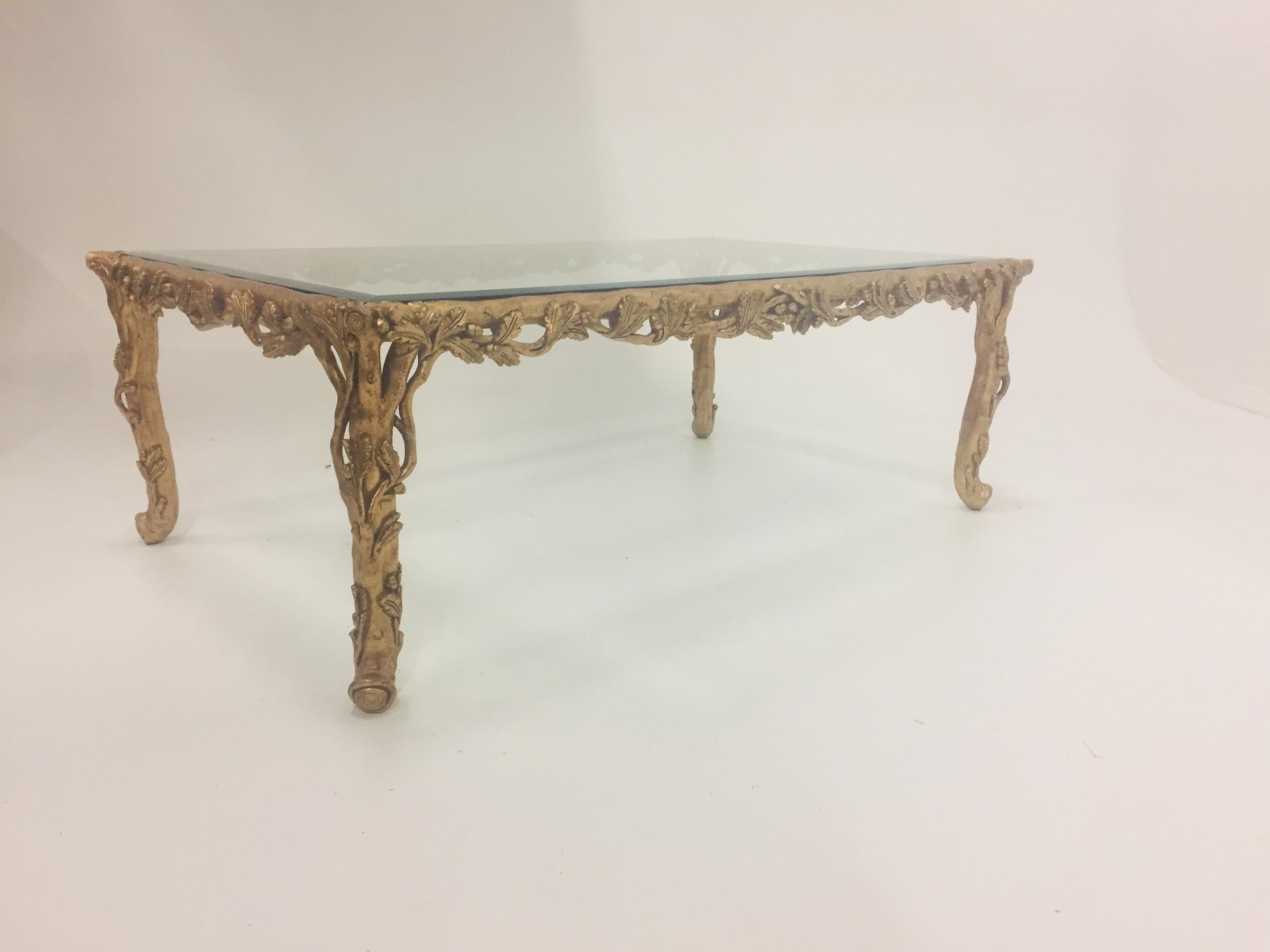 Very glamorous gilded hand carved wood rectangular coffee table having ornate leafy decoration on the base and heavy bevelled glass top.
 