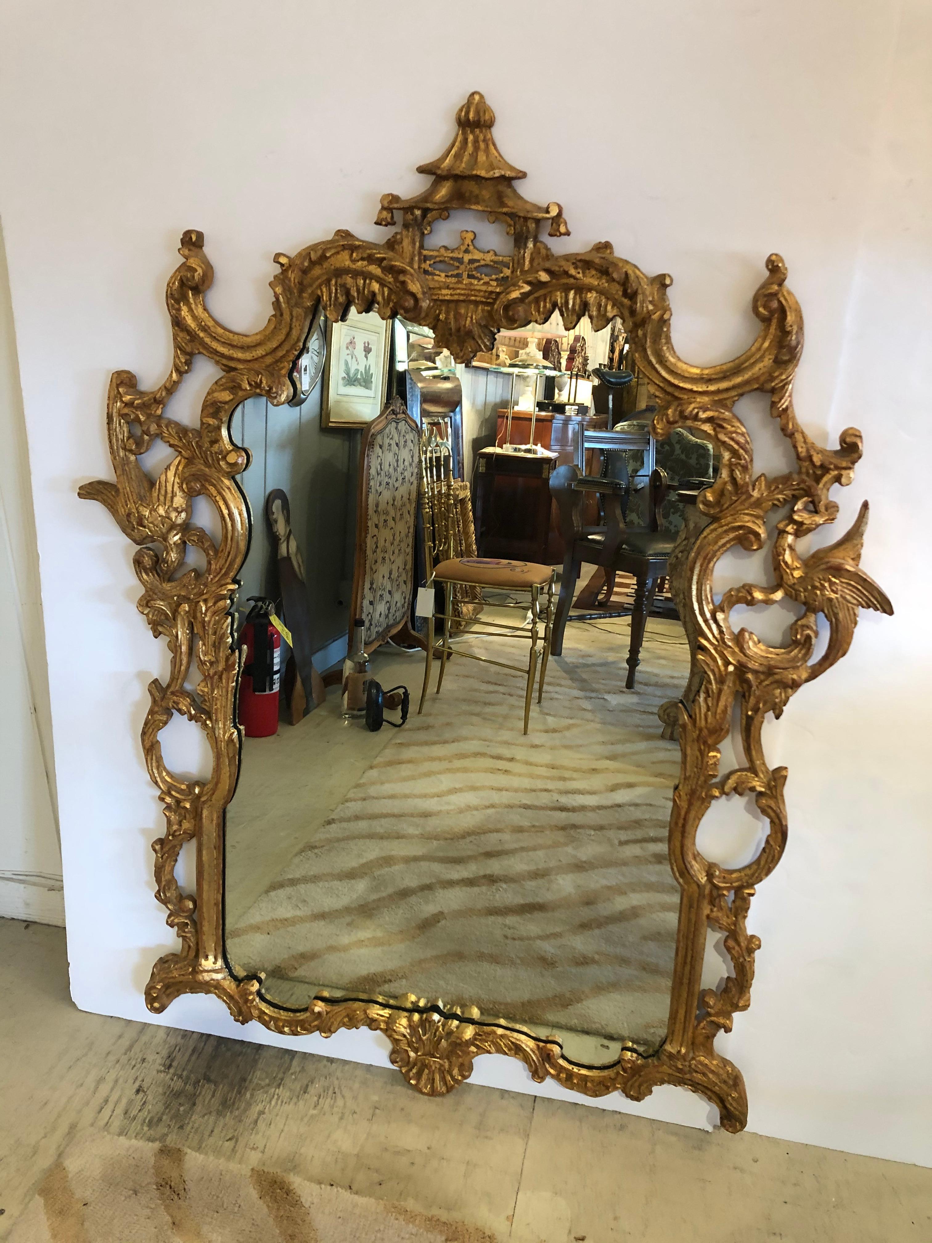 A spectacular large carved Italian giltwood Chinese Chippendale style mirror having pagoda at the top, curlicues and ornate birds and foliage around the frame with wonderful aged patina.